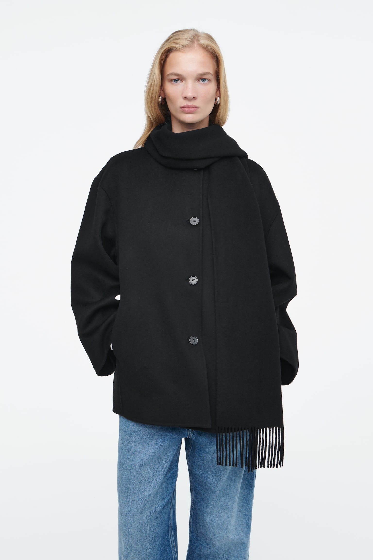 Shaped in an enveloping, oversized cut, this black COS jacket is crafted from double-faced RWS wool that's blended with TENCEL™ Lyocell, lending it a beautifully fluid hand feel. It's designed with dropped shoulders, wide sleeves and a blanket-style fringed scarf, which you can leave draped along the front or wrapped effortlessly over one shoulder. Style it with the matching skirt. Oversized fit Button closure, side slip pockets