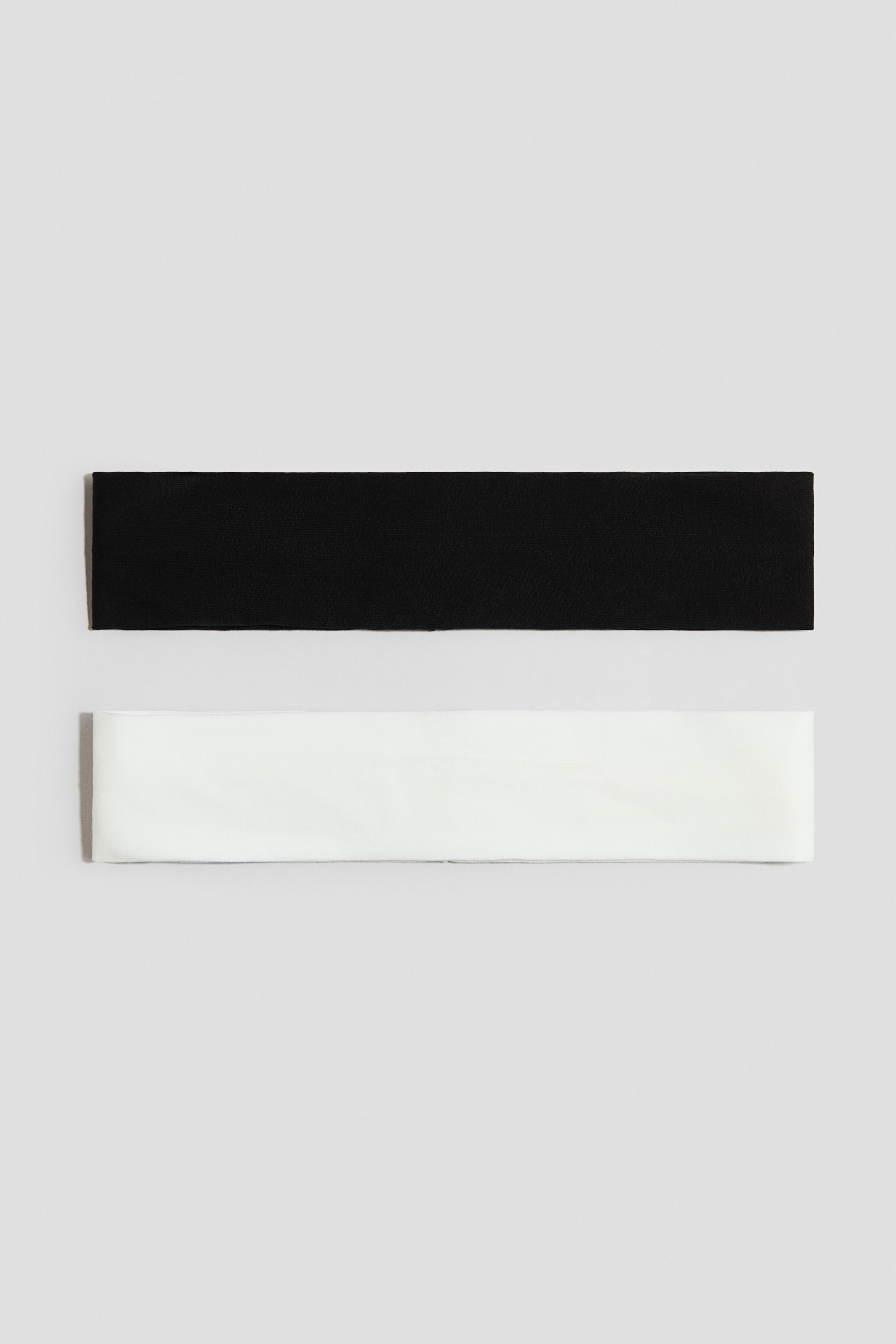 Ampliar la imagen: Dos bandas rectangulares están colocadas horizontalmente, una encima de la otra. La banda superior presenta un color negro y una superficie texturizada, mientras que la banda inferior presenta un color blanco y una superficie lisa.