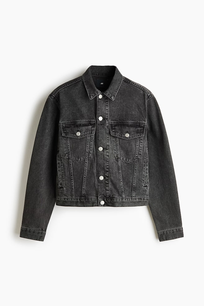 A dark grey denim jacket is shown from the front, featuring a classic spread collar, a button-down fastening with silver-toned metal buttons, and two chest pockets with buttoned flaps. The jacket features a washed finish, vertical panel seams, and long sleeves with buttoned cuffs. - 1