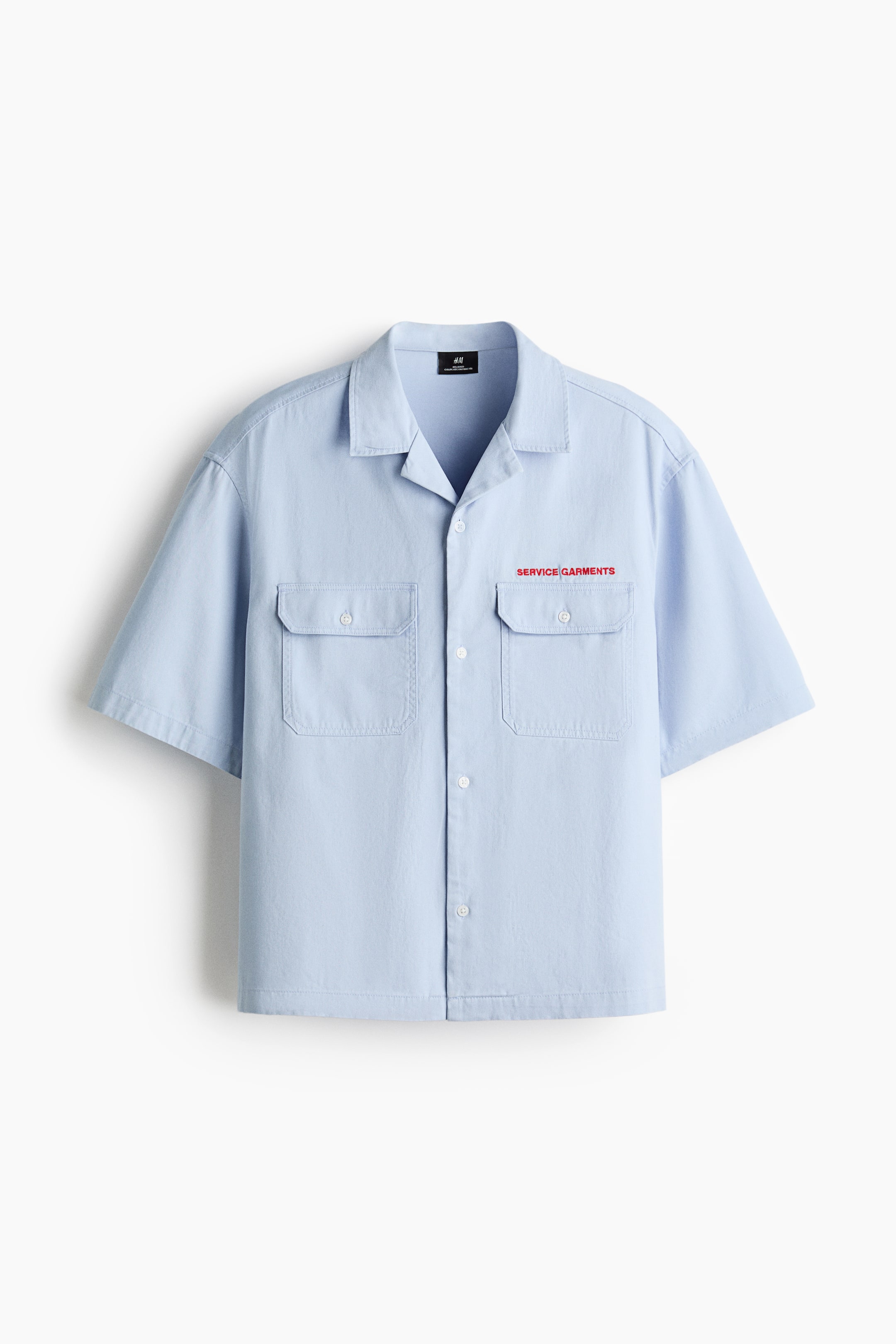 View larger image: A light blue short-sleeved shirt is presented as FRONT, featuring a camp collar and a button-front. It is showcasing two buttoned flap pockets on the chest, with red "SERVICE GARMENTS" text embroidered above the right pocket.