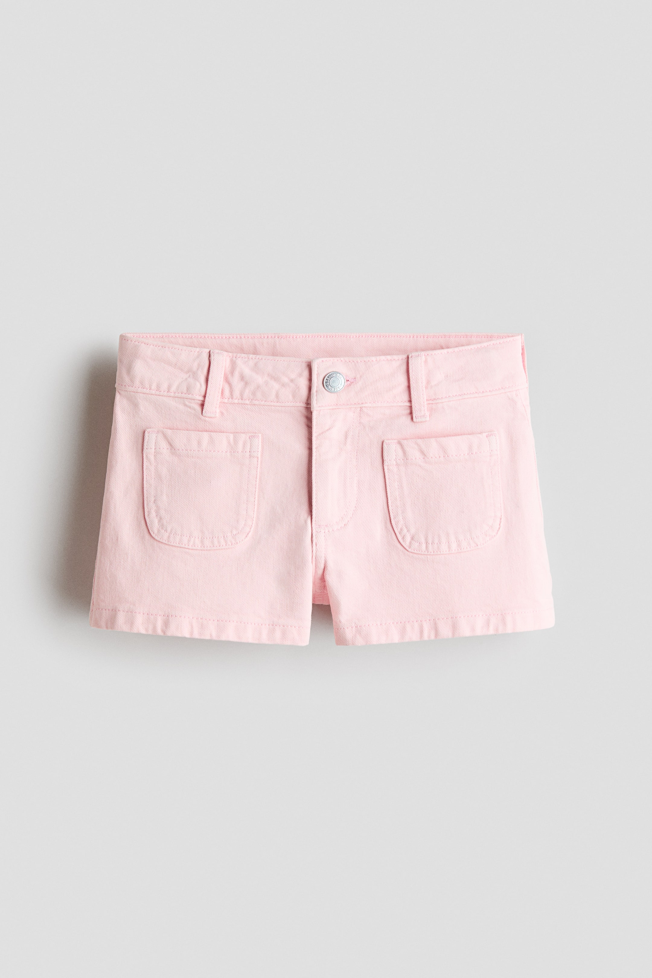 Ver imagen más grande: Shorts rosa de corte relajado en denim de algodón, vistos de frente, con cinturilla con trabillas para cinturón, cierre de botón y dos bolsillos de parche redondeados en la parte delantera.