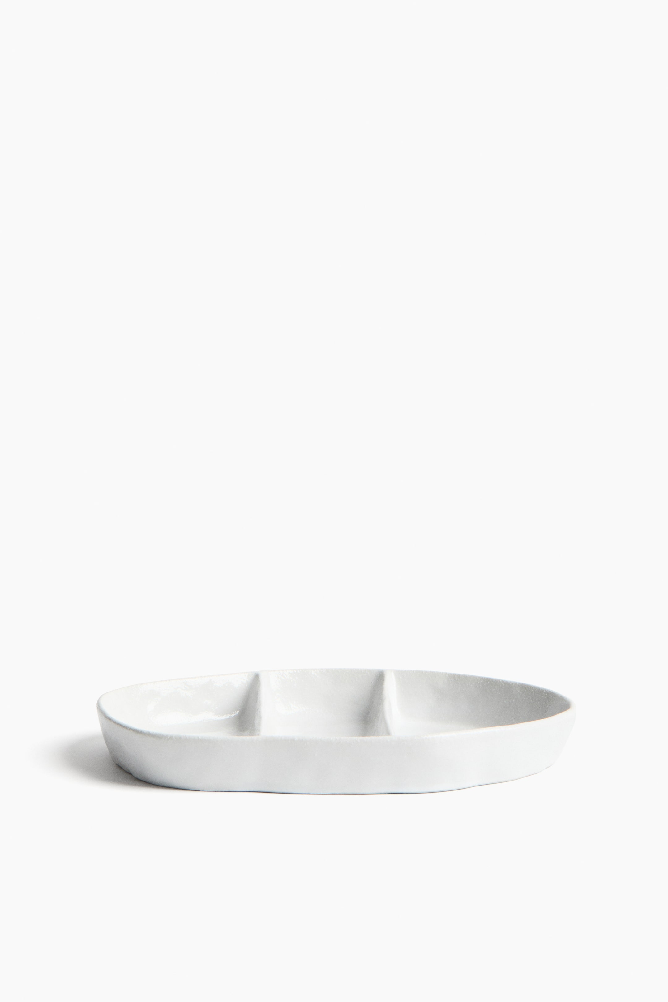 View larger image: A white oval serving dish faces forward, showcasing three distinct compartments. The dish features a subtle textured surface.
