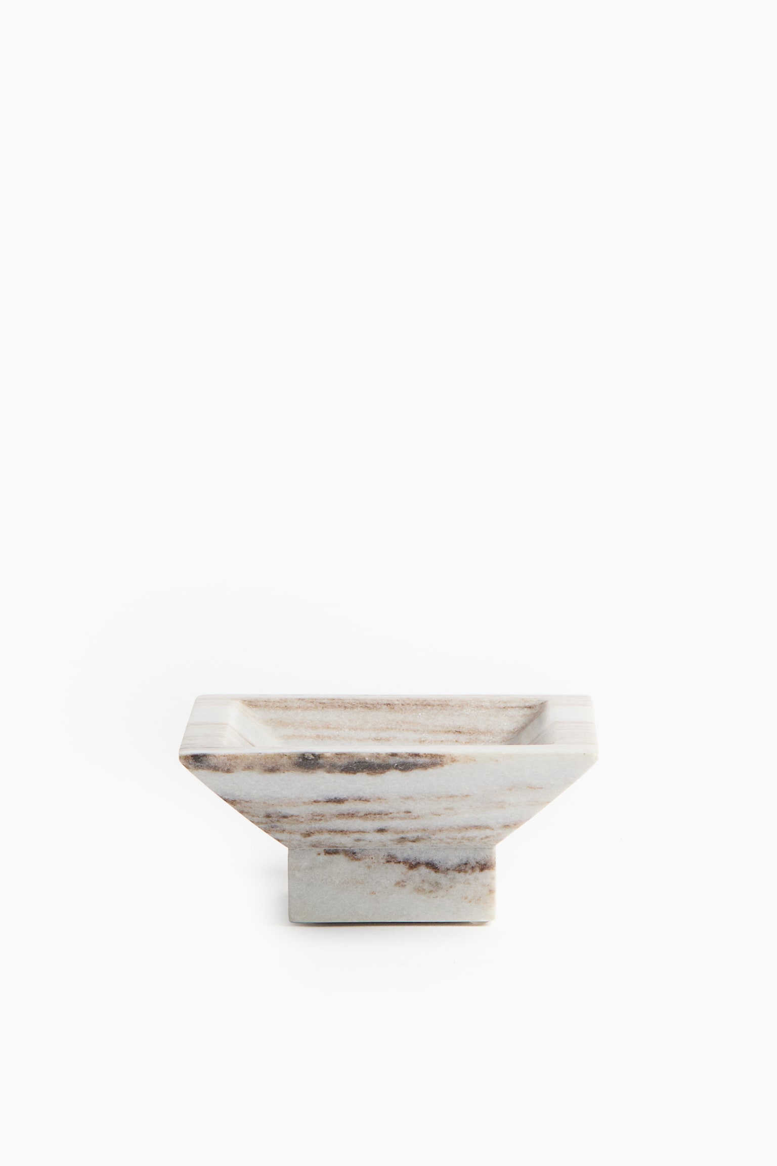 A square marble pedestal dish stands facing front, featuring a flared square basin supported by a smaller block base. The dish displays natural horizontal beige and brown veining across its off-white marble surface.