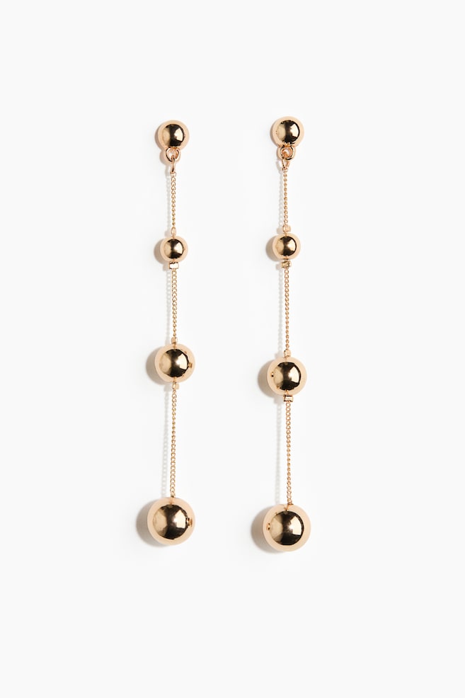 Une paire de longues boucles dâoreilles pendantes aux tons dorÃ©s est prÃ©sentÃ©e de face, avec des sphÃ¨res mÃ©talliques hautement polies, de tailles graduÃ©es, reliÃ©es par de dÃ©licates chaÃ®nettes Ã  maillons. Suspendues verticalement, chaque boucle dâoreille commence par une petite puce en dÃ´me, puis se prolonge par des sphÃ¨res de tailles croissantes, se terminant par la plus grande sphÃ¨re en bas. - 1