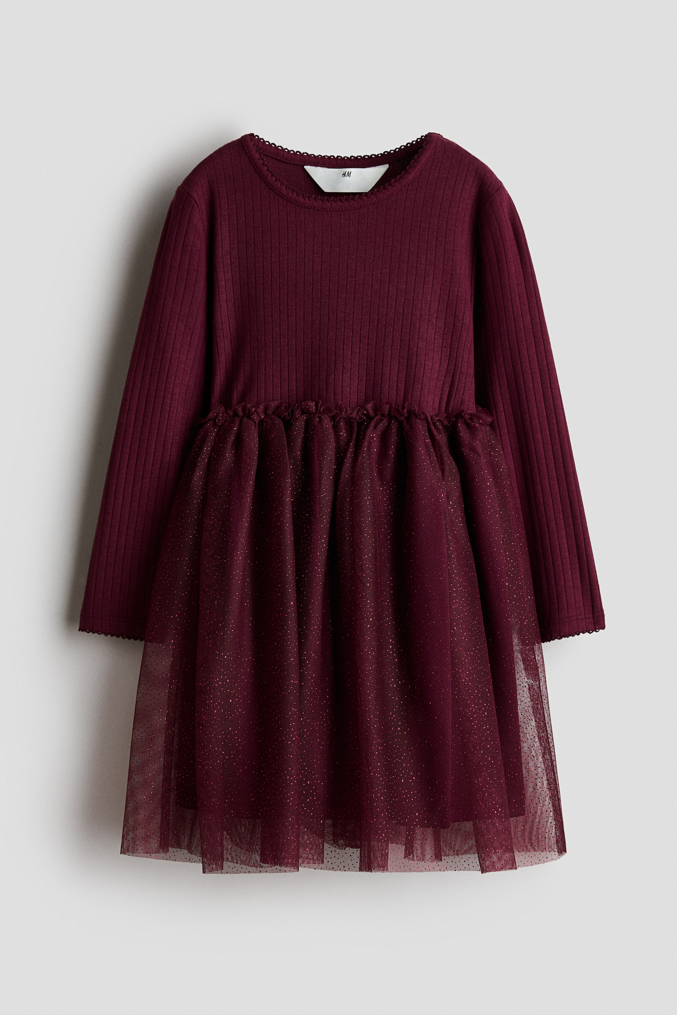 View larger image: A dark burgundy dress is shown from the front, featuring a long-sleeved, ribbed jersey bodice with a round neckline and picot trim at the collar and cuffs. The dress is designed with a small frill trim at the waist and a flared, lined tulle skirt sparkling with fine glitter.