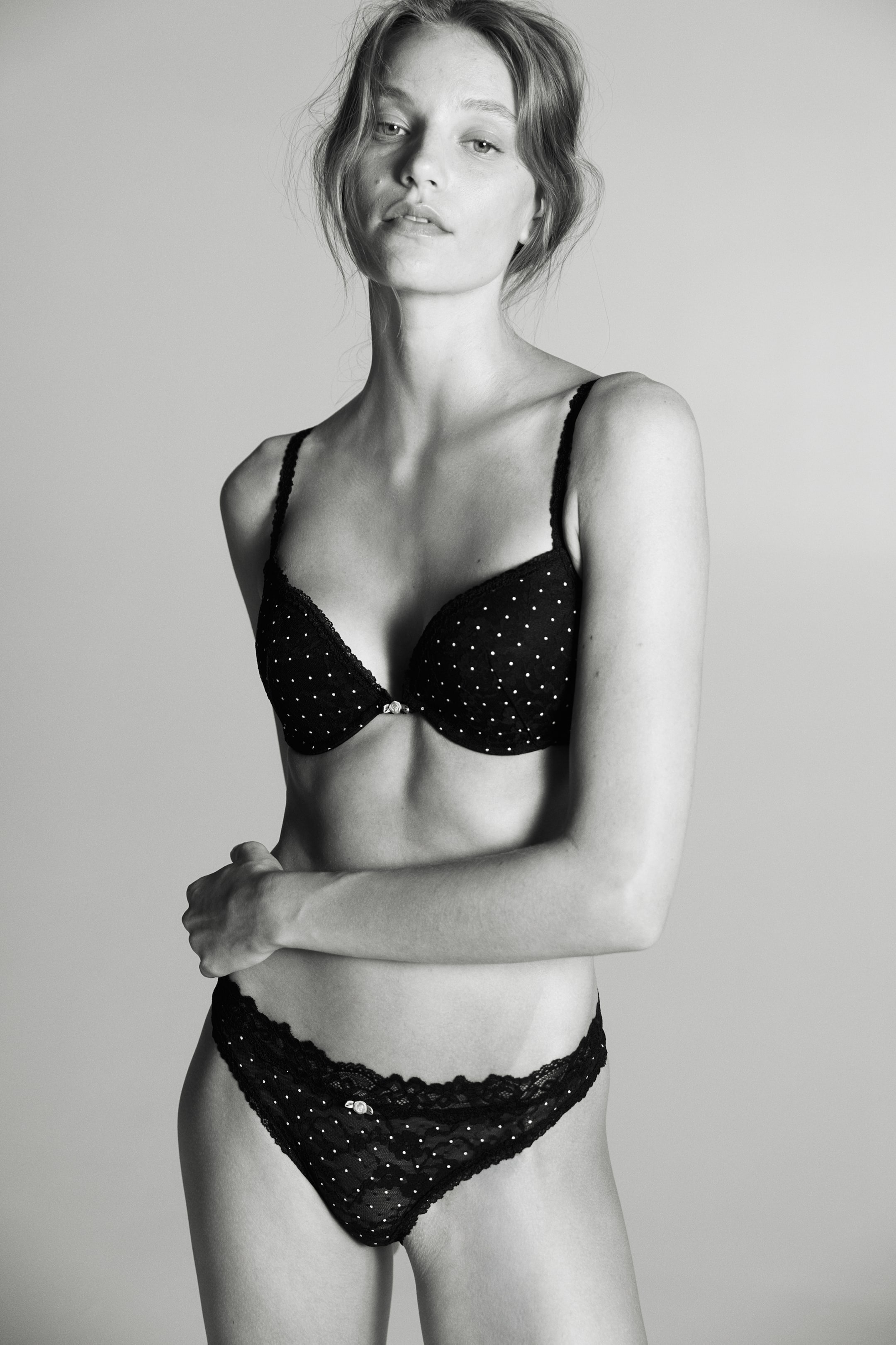 View larger image: Lace briefs featuring a low-rise waist and a polka-dot pattern are shown from the front on a model. The briefs feature a scalloped lace waistband with a small decorative charm at the centre and high-cut legs, styled with a matching underwired polka-dot bra.
