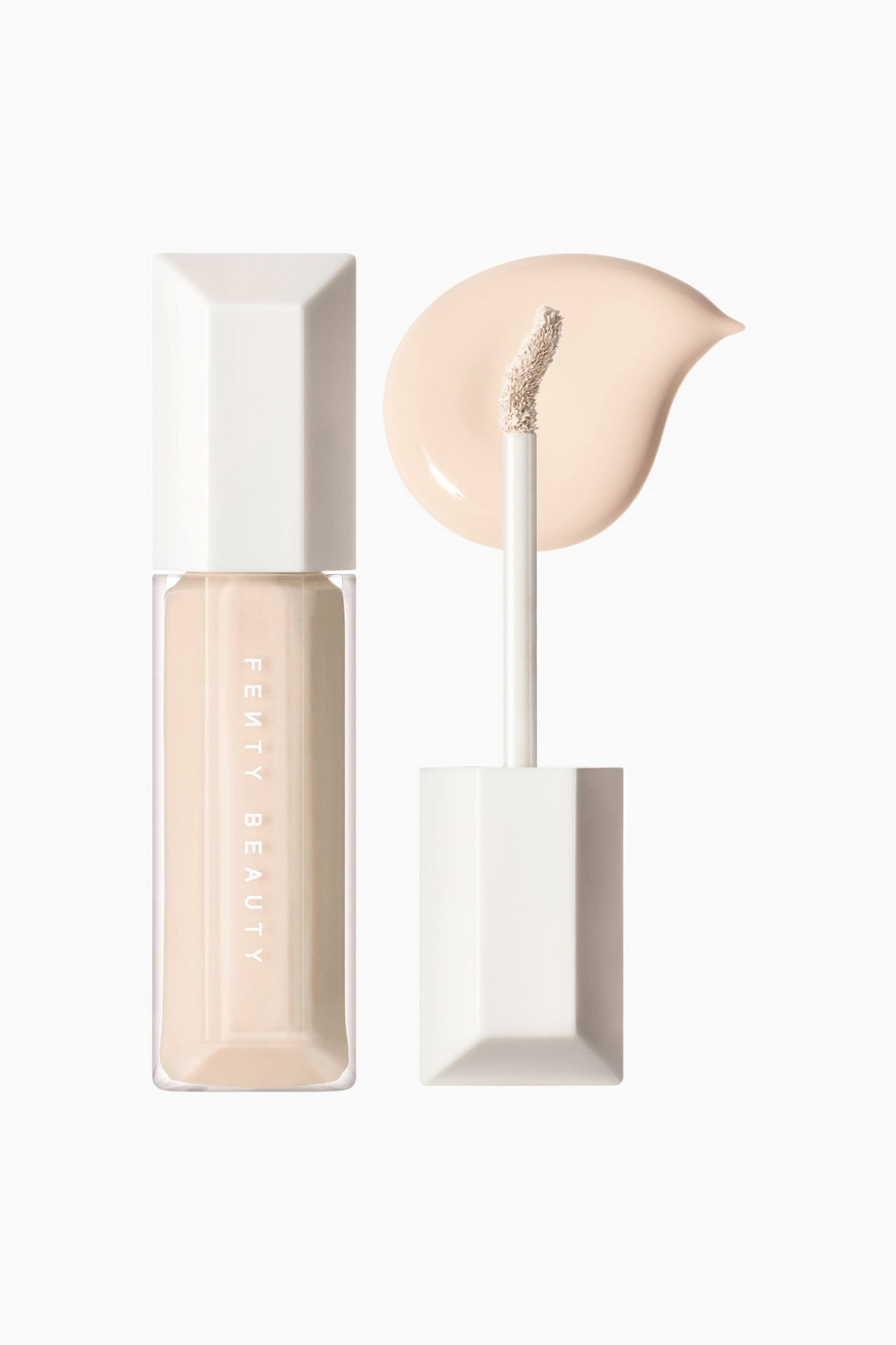 Visa större bild: We're Even Hydrating Longwear Concealer visas i en genomskinlig, facetterad rektangulär flaska med vit kork, stående bredvid sin avskruvade applikatorstav med en böjd, vinklad doe-foot-spets. Ett slätt, droppformat swatch av den ljusbeige flytande formulan ligger direkt bakom applikatorns spets och visar upp dess nyans och krämiga textur.
