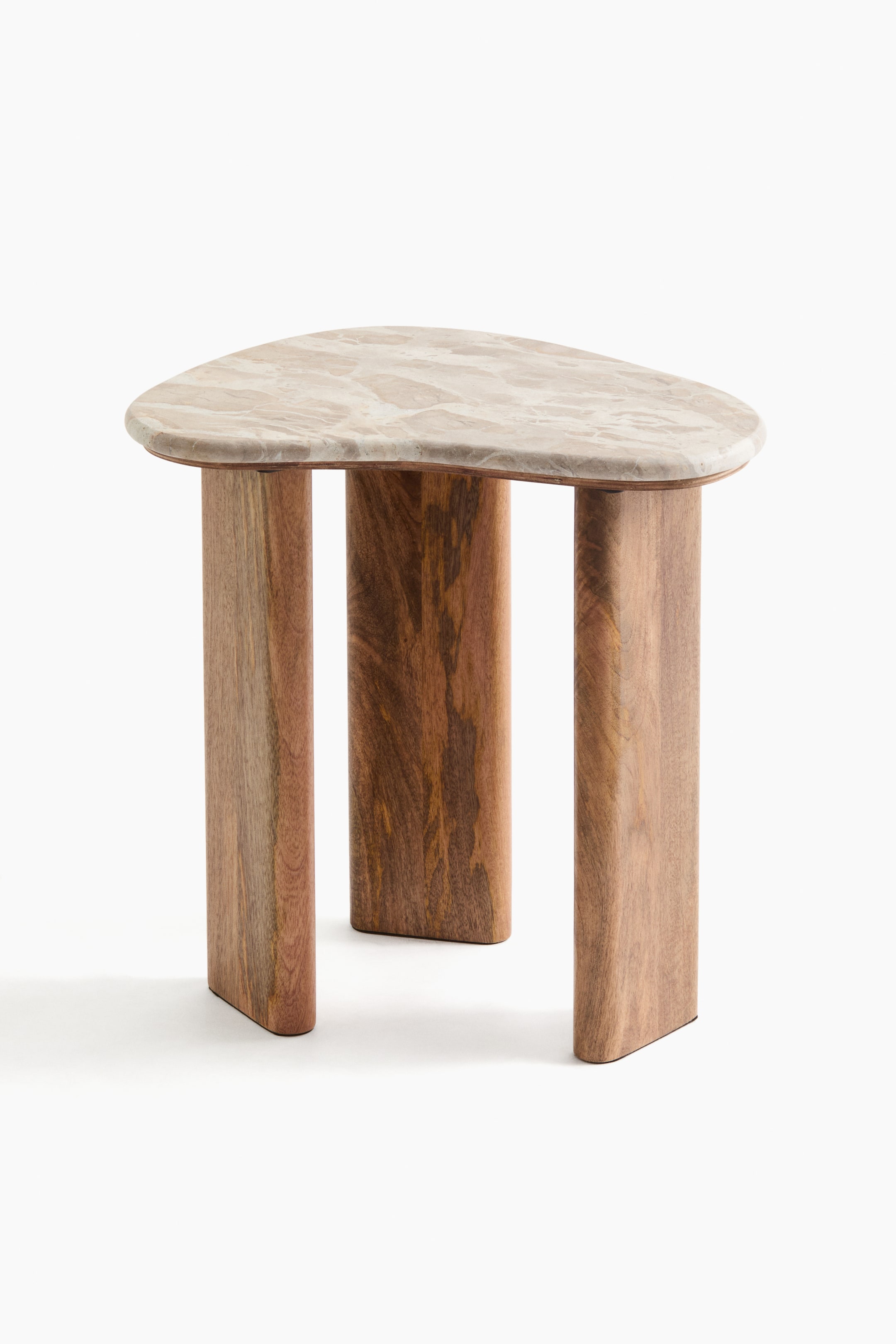 View larger image: An asymmetrical side table is shown front-on, featuring an irregular, rounded, light-beige marble tabletop with subtle dark veining. It rests on three thick, oblong wooden legs showcasing the natural grain and varying brown tones.