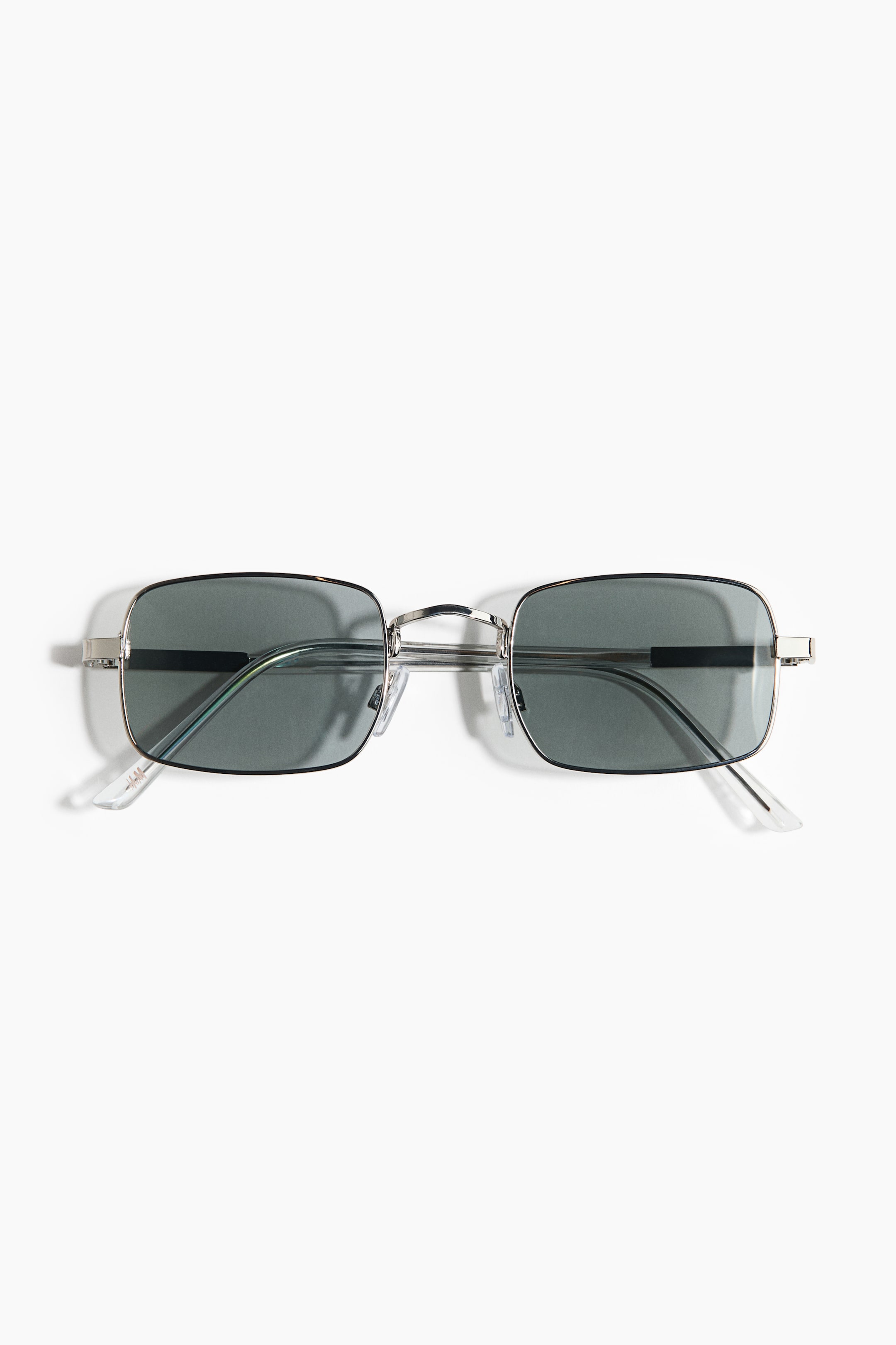 View larger image: These sunglasses are displayed in a front-facing view, highlighting their rectangular dark-tinted lenses. They feature thin, silver-toned metal frames, adjustable clear nose pads, and metal sidepieces with transparent tips.