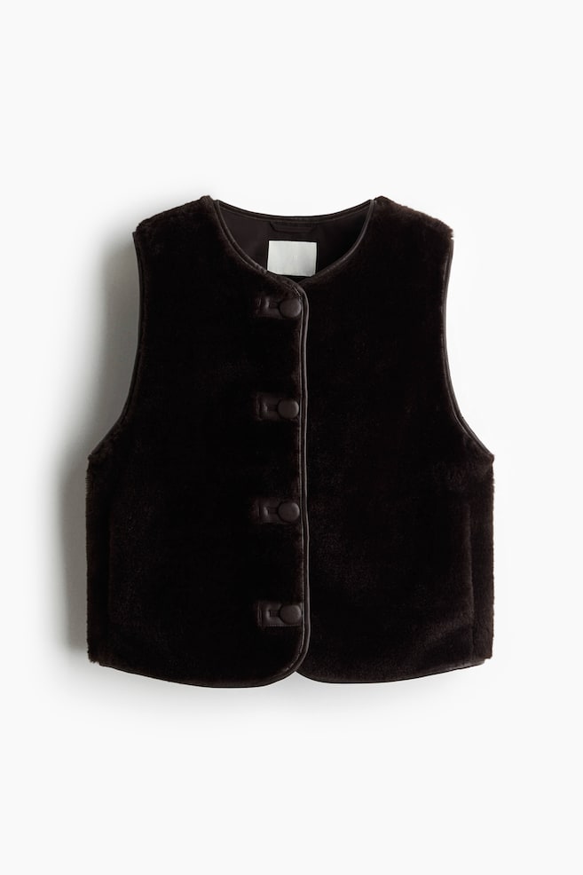 En mørkebrun faux fur vest præsenteres forfra, med en rund halsudskæring og en frontlukning med fire mørke, løkke-og-knap lukninger. Mørke kanter fremhæver frontåbningen. - 1