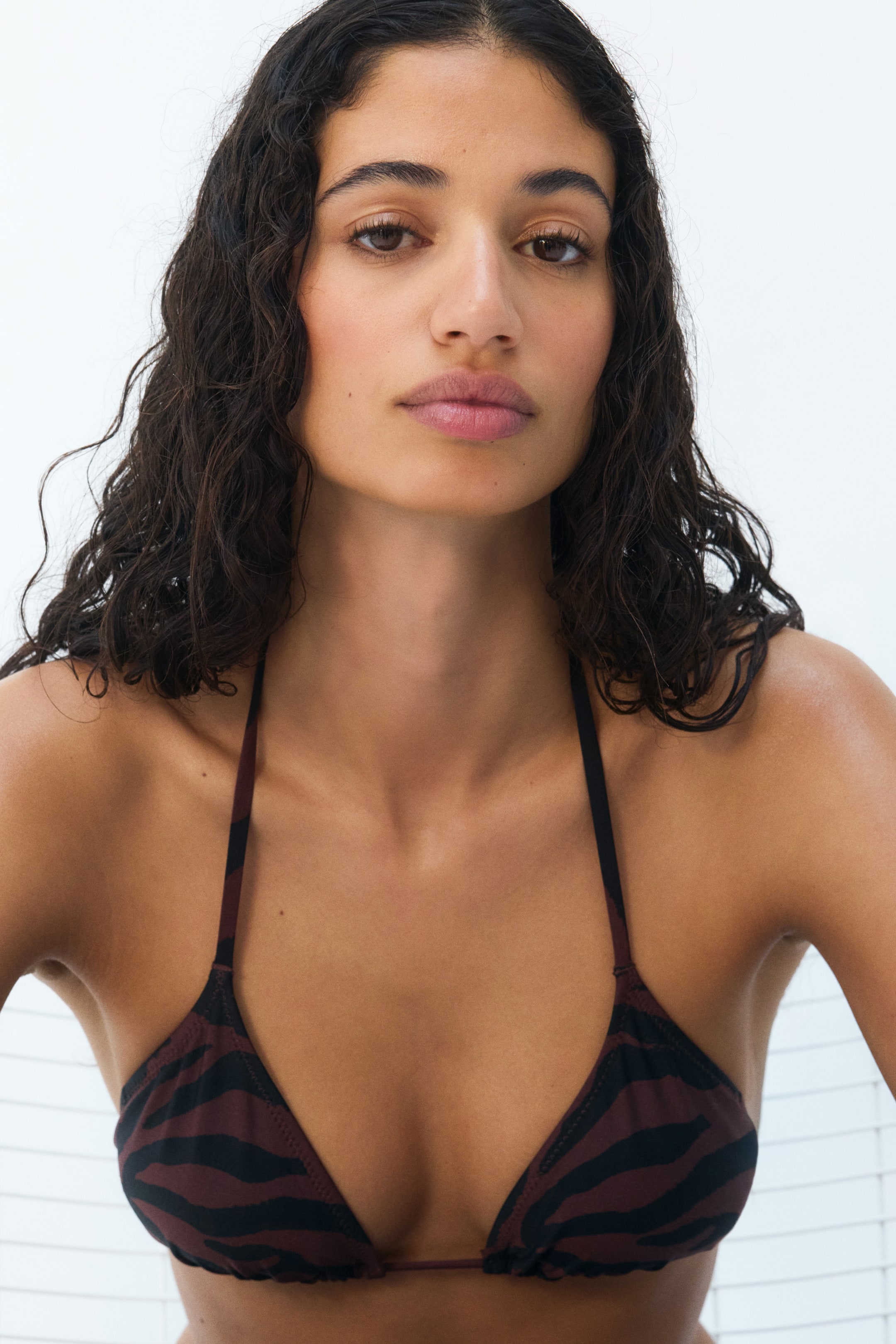 View larger image: A triangle bikini top featuring dark brown fabric with black zebra stripes and thin halter straps. The cups display subtle gathering along their bottom edges.