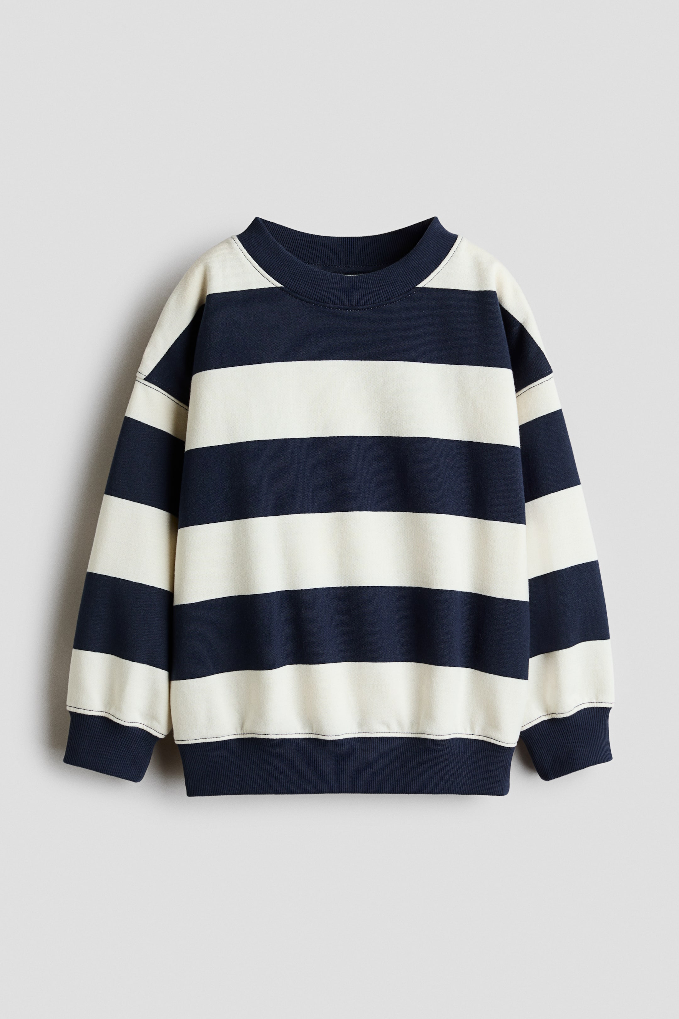 View larger image: A front view of a long-sleeved sweatshirt showcasing wide horizontal navy blue and cream stripes. The garment features a round ribbed neckline, dropped shoulders, and solid navy blue ribbed cuffs and hem.