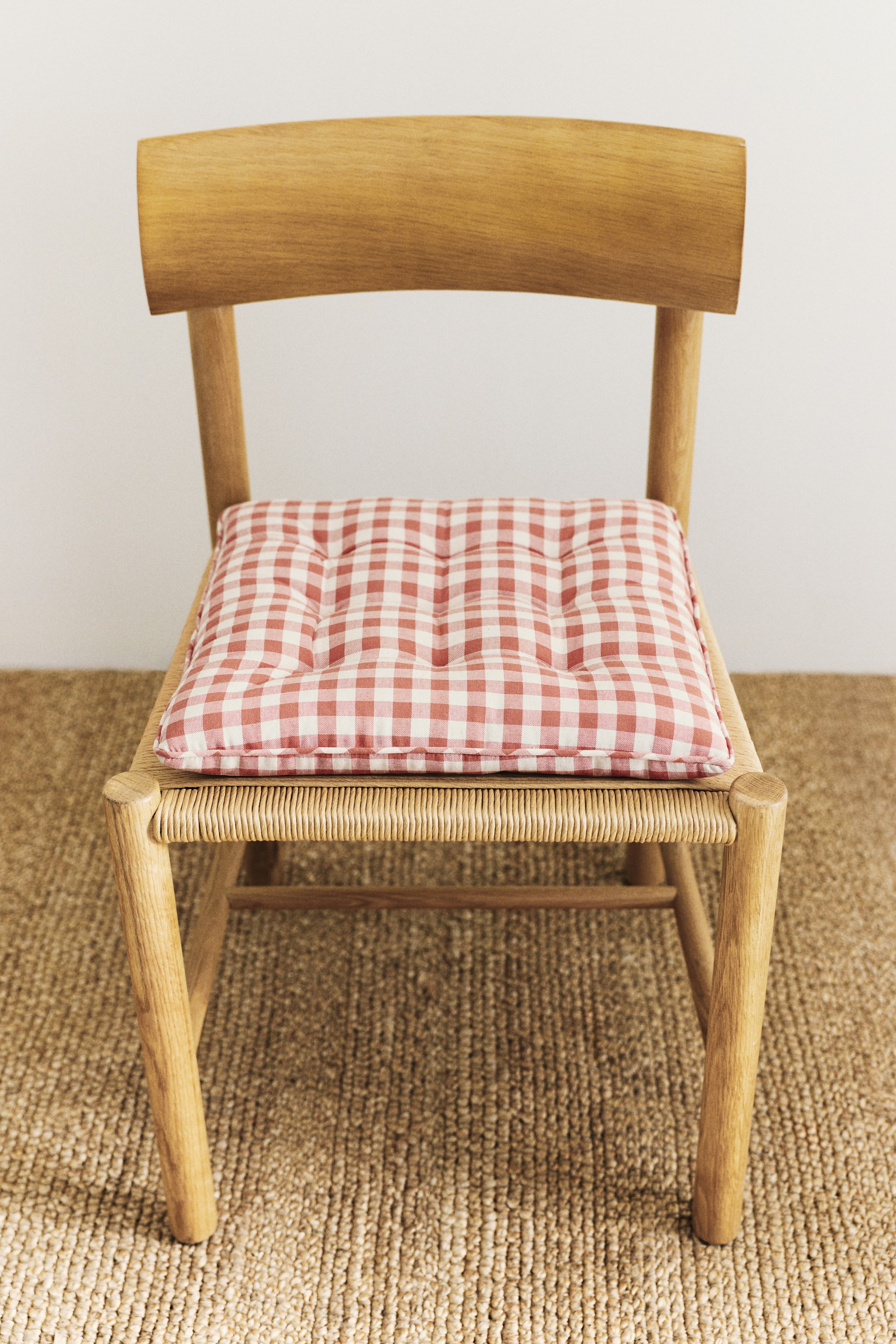 View larger image: The front of the padded seat cushion showcases a red and white gingham-check pattern on a cotton weave, accentuated with quilt knots.