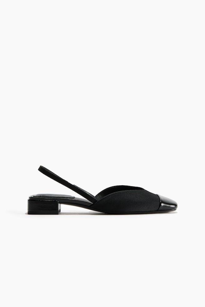 Ein schwarzer Slingback-Schuh ist in seitlichem Profil zu sehen und verfÃ¼gt Ã¼ber ein mattes Obermaterial aus Stoff, eine kontrastierende glÃ¤nzende Zehenkappe aus Lackleder und einen niedrigen, rechteckigen Blockabsatz. - 1