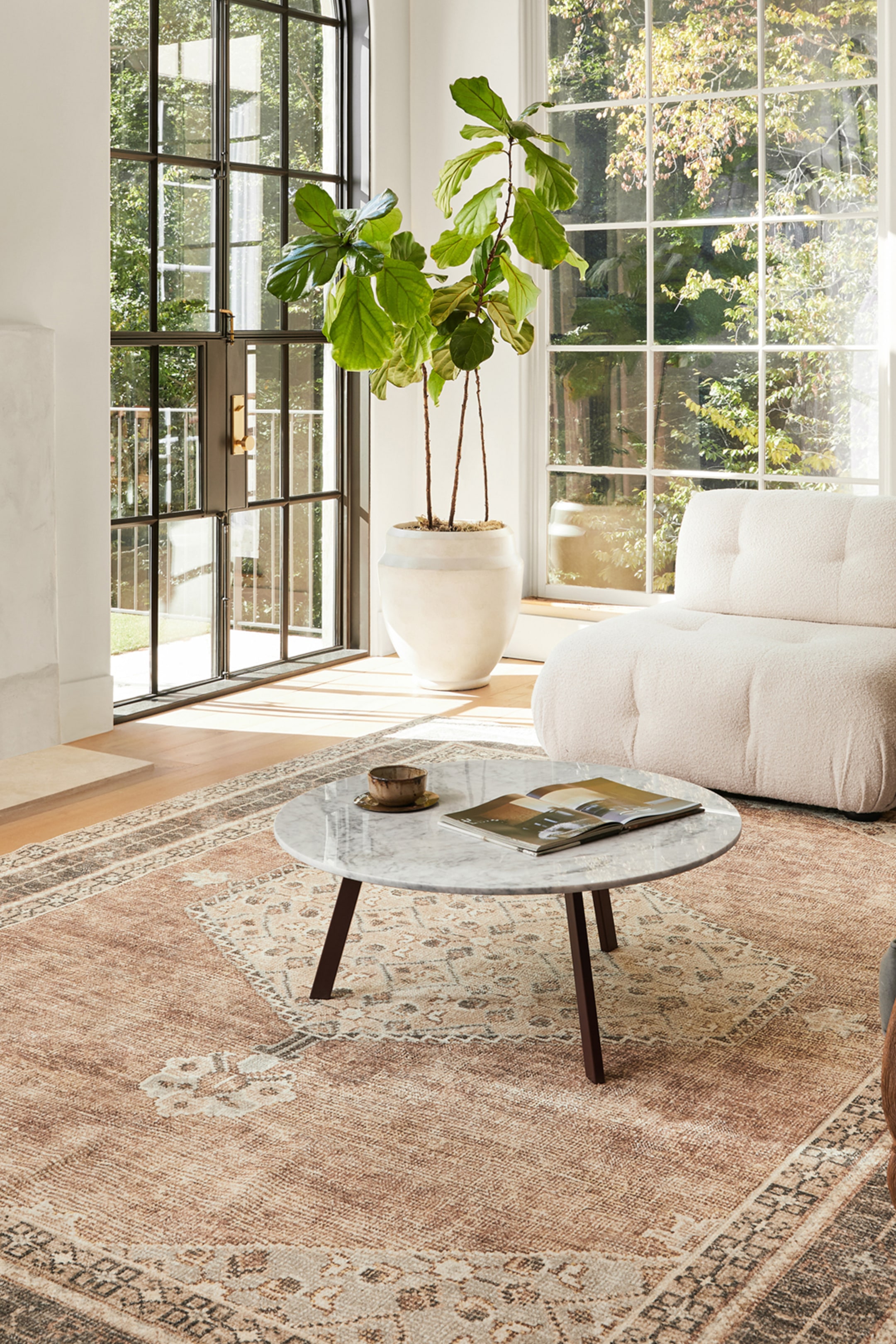 View larger image: A rectangular rug showcases a distressed traditional pattern in shades of terracotta, beige, grey, and dark brown. It features a central medallion-like design and a prominent border.