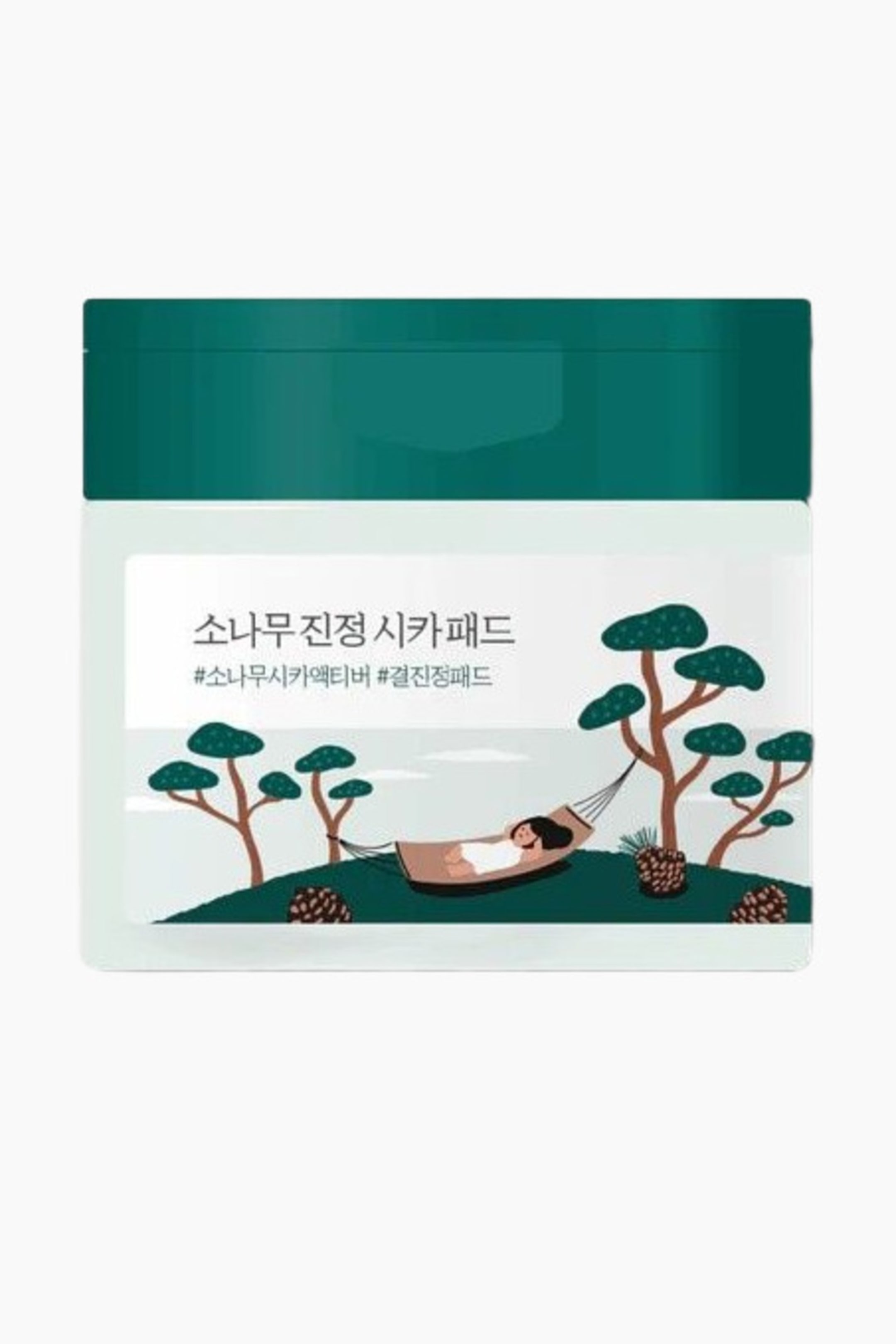 Se større billede: En rektangulær beholder vender fremad, med et mørkt teal-farvet låg og en lysfarvet krop. Kroppen viser en etiket med koreansk tekst og en illustration af en person i en hængekøje mellem stiliserede fyrretræer på grønne bakker.
