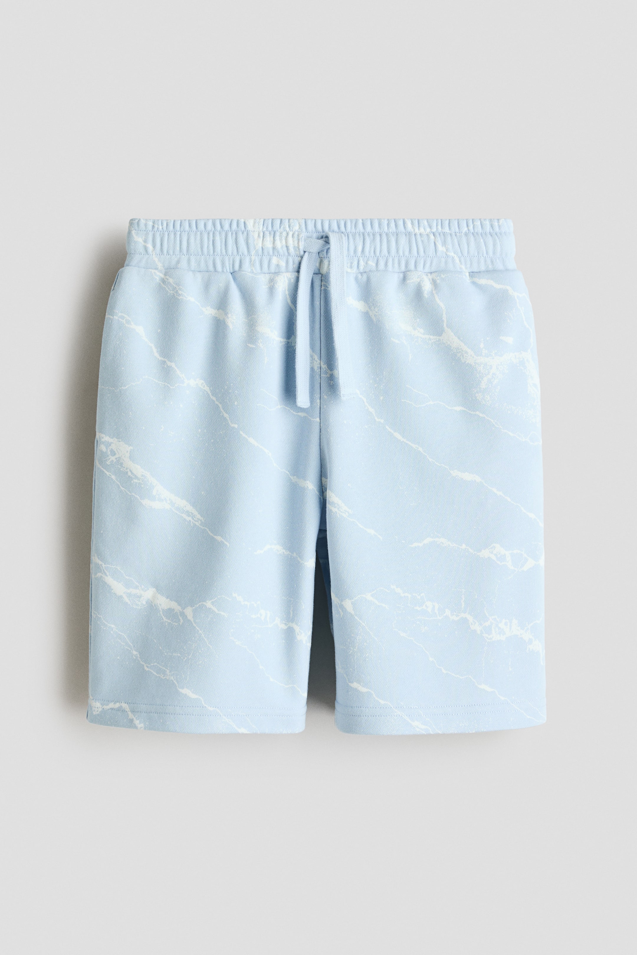 Größeres Bild anzeigen: Shorts aus leichtem, bedrucktem Sweatshirtstoff in Hellblau mit einem weißen, marmorähnlichen Muster, einem elastischen Kordelzugbund, dezenten Seitentaschen und unversäumten Säumen, alles aus der Vorderansicht betrachtet.