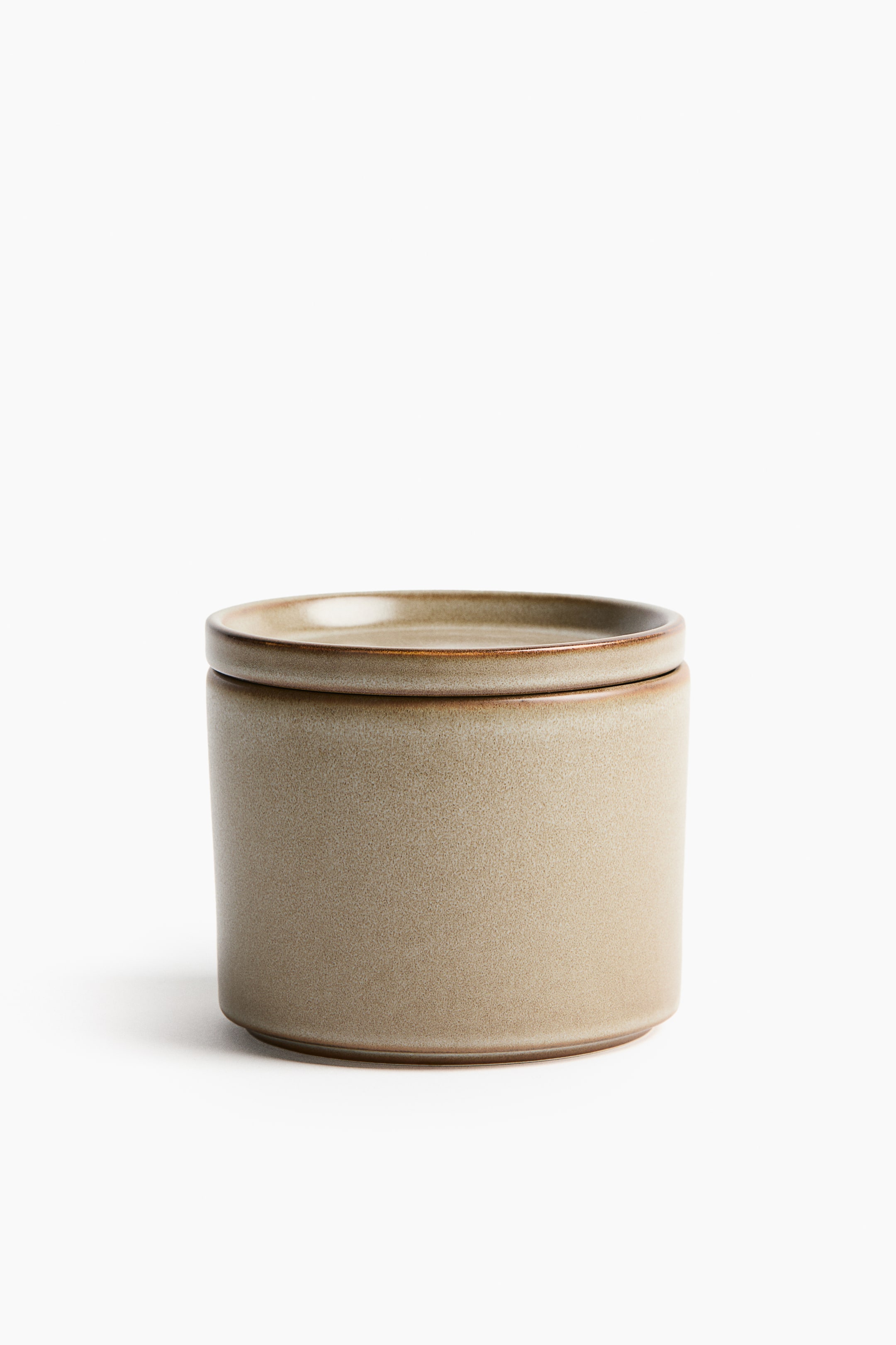 View larger image: A small stoneware jar and lid are visible from the FRONT, featuring a cylindrical body and a flat lid with a subtle lip designed for stacking. Its surface is displaying a variegated beige reactive glaze.