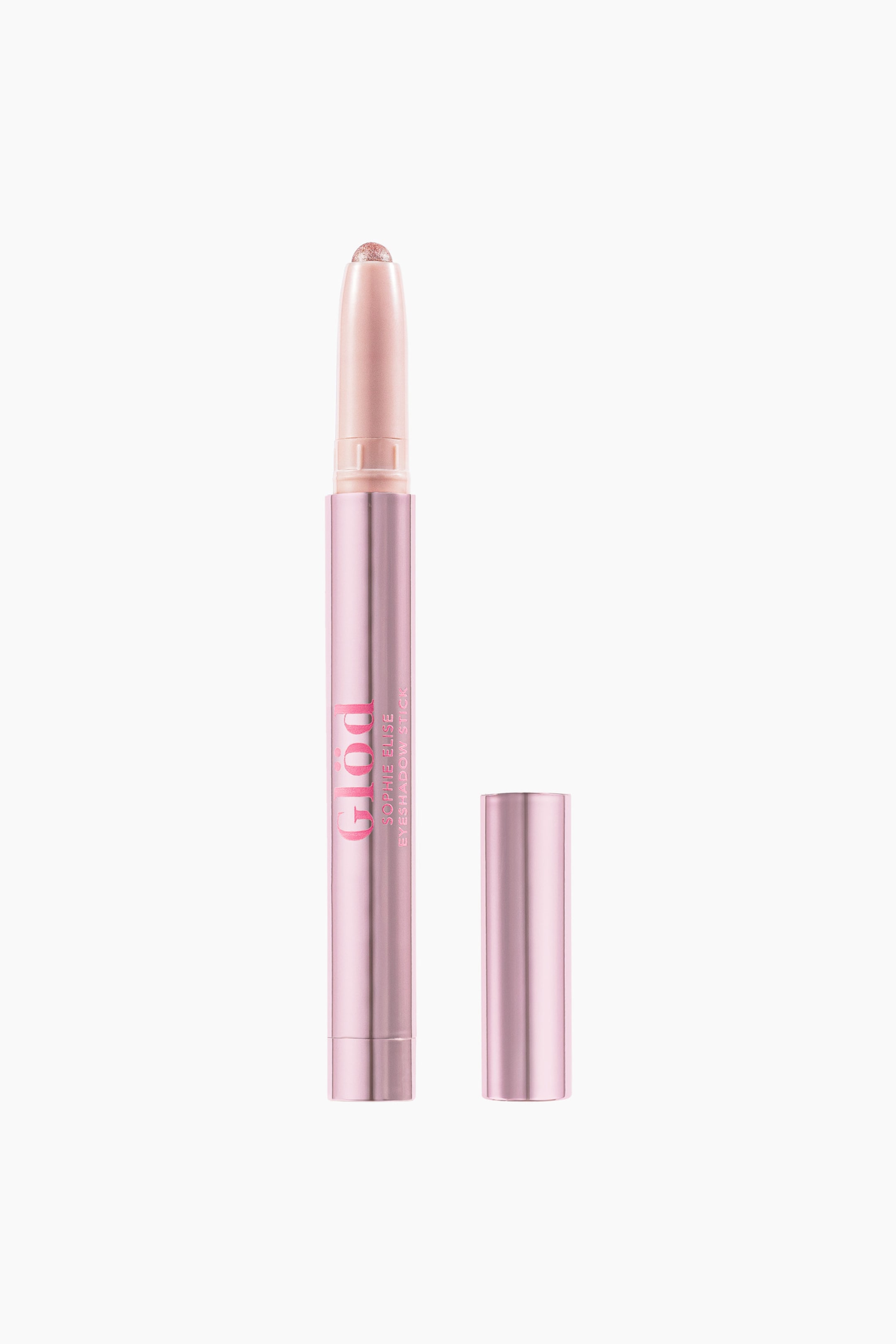 Se større billede: En øjenskyggestift står oprejst, med et metallisk pink hylster og en glitrende fersken-pink spids, og dens matchende låg ligger ved siden af. Hylstret viser "GLOD SOPHIE ELISE EYESHADOW STICK" trykt lodret.