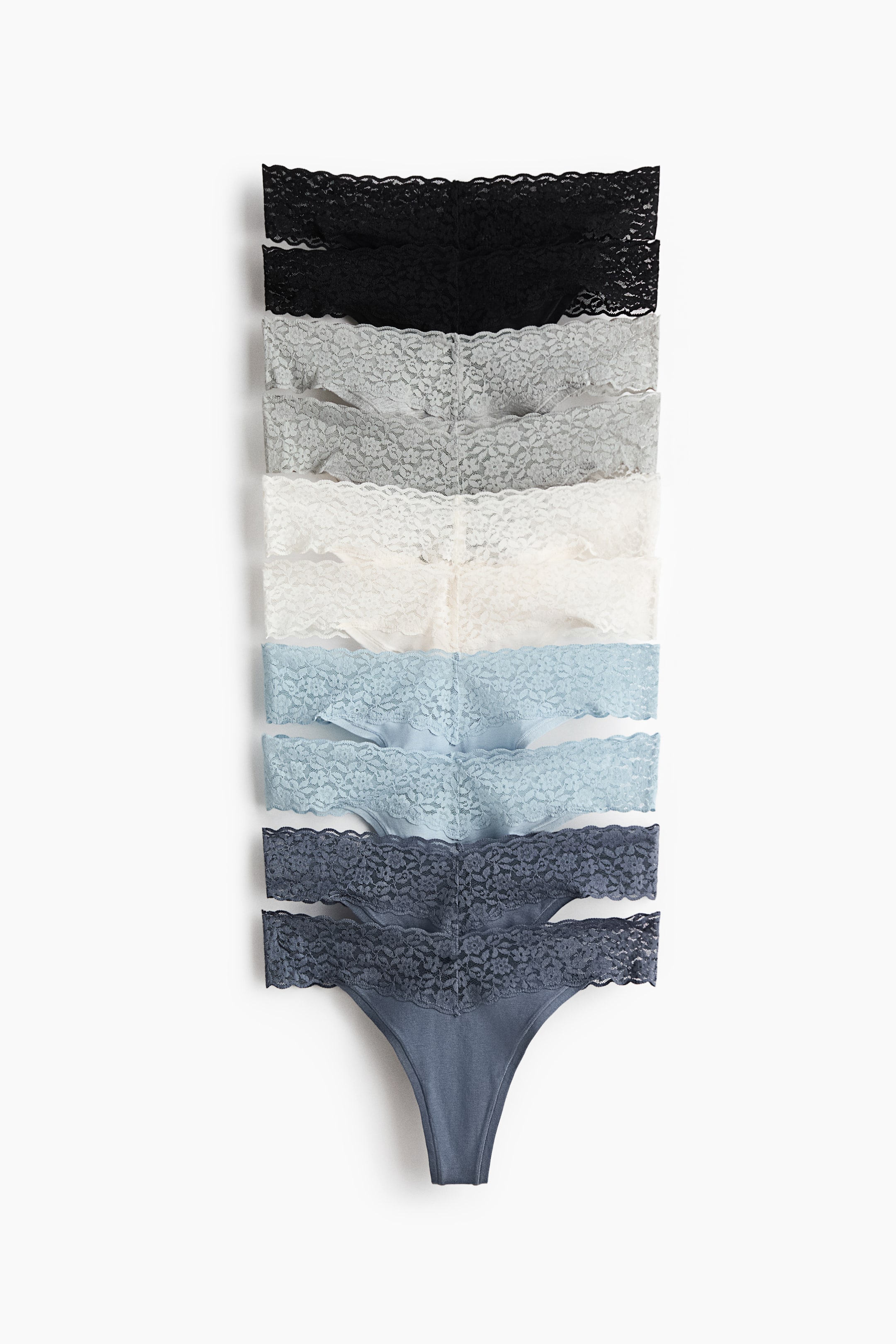 查看大圖: 六條丁字褲以縱向堆疊展示正面，呈現由黑色至淺灰、白色及多種藍色的漸層色彩。每條均採用低腰V形蕾絲腰頭，並備有襠部內襯。