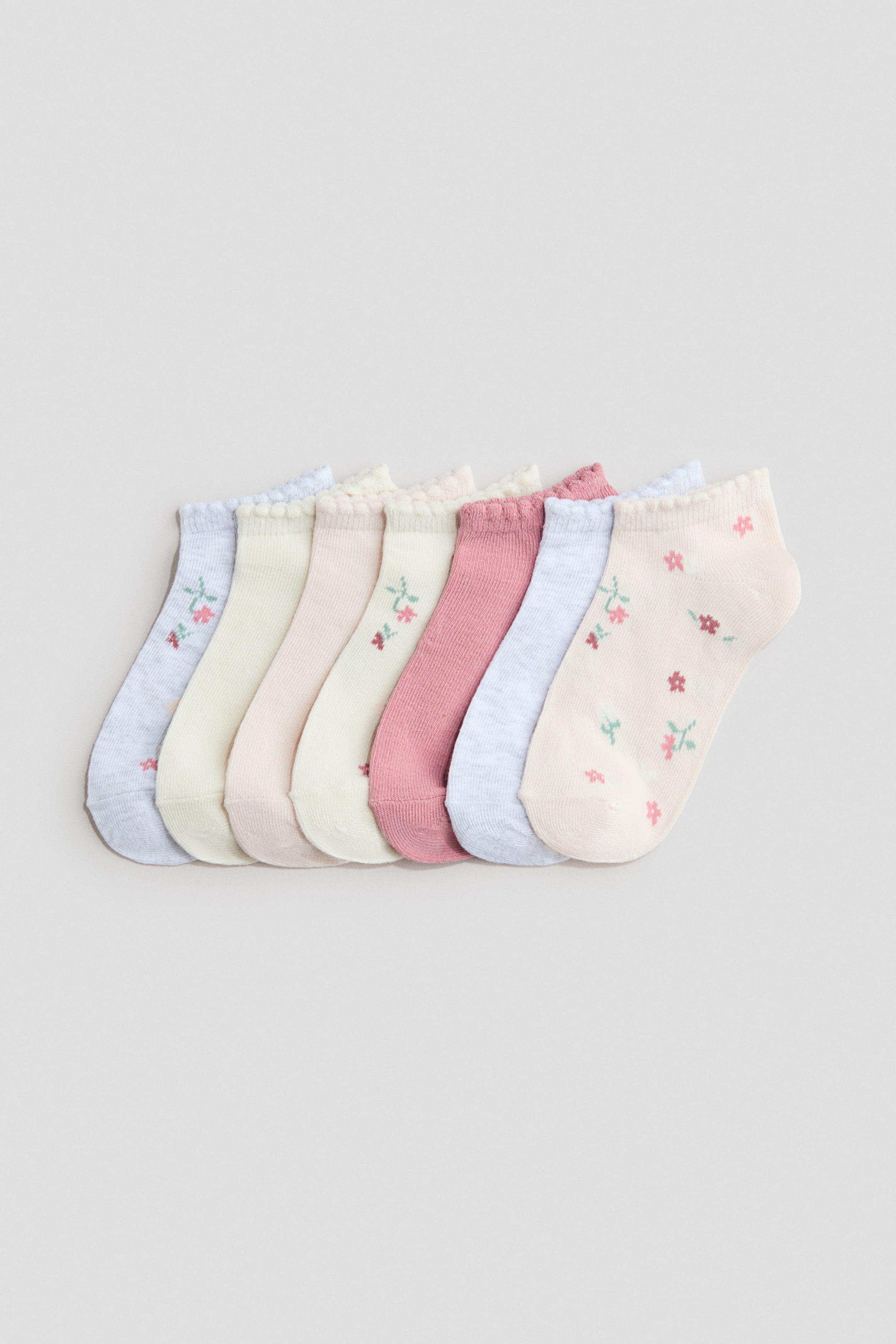 Büyük resmi görüntüle: Yedi parçadan oluşan ince örgü spor çorap seti yan yana sergileniyor. Her çorap, kenarları dalgalı elastik üst kısımlarla öne çıkıyor. Çoraplar, çeşitli pastel tonlarda görünüyor ve bazıları küçük çiçek desenleriyle süslenmiş.