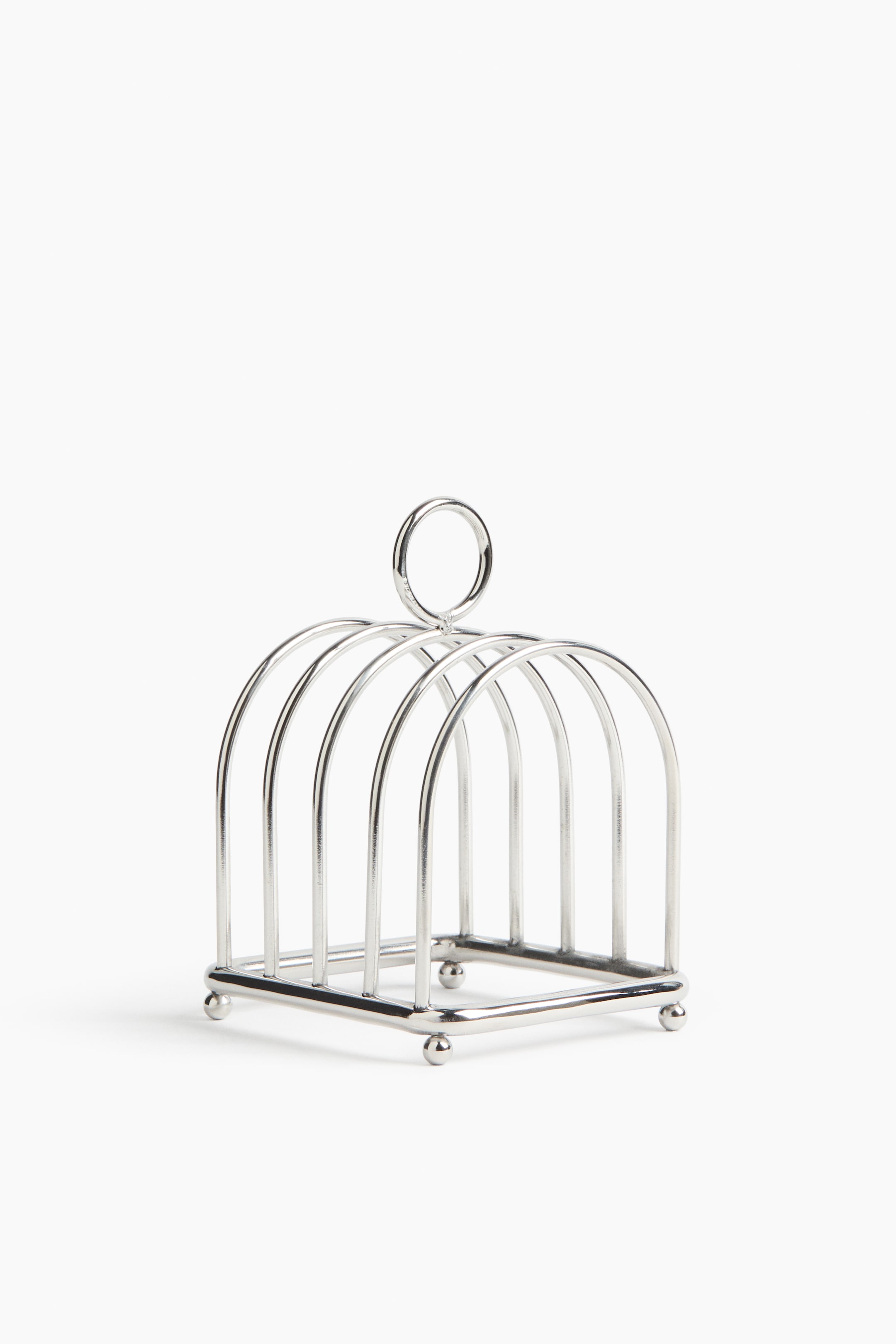 View larger image: A silver-toned metal toast rack stands with a rectangular base supported by four spherical feet. It features multiple arched dividers forming compartments, and a circular handle rises from the center top.