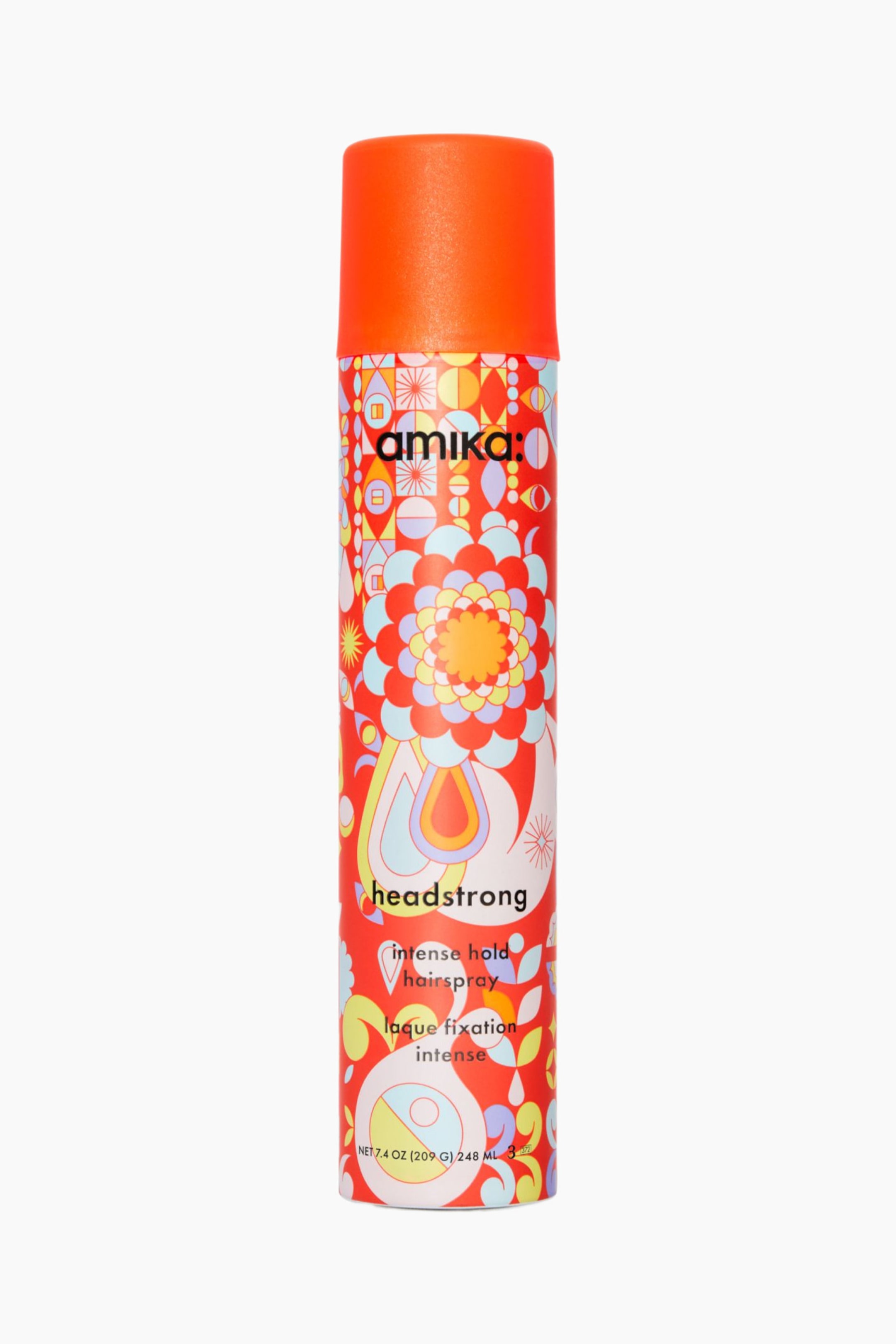 Se større billede: Headstrong Intense Hold Hairspray står oprejst og fremviser en livlig orange cylindrisk hætte og en farverig, retroinspireret krop dekoreret med blomstrede og geometriske motiver i rød, orange, blå og gul. Den forreste dåse viser det sorte "amika:"-logo nær toppen, med "headstrong" og "intense hold hairspray" trykt med små sorte bogstaver hen over midten.