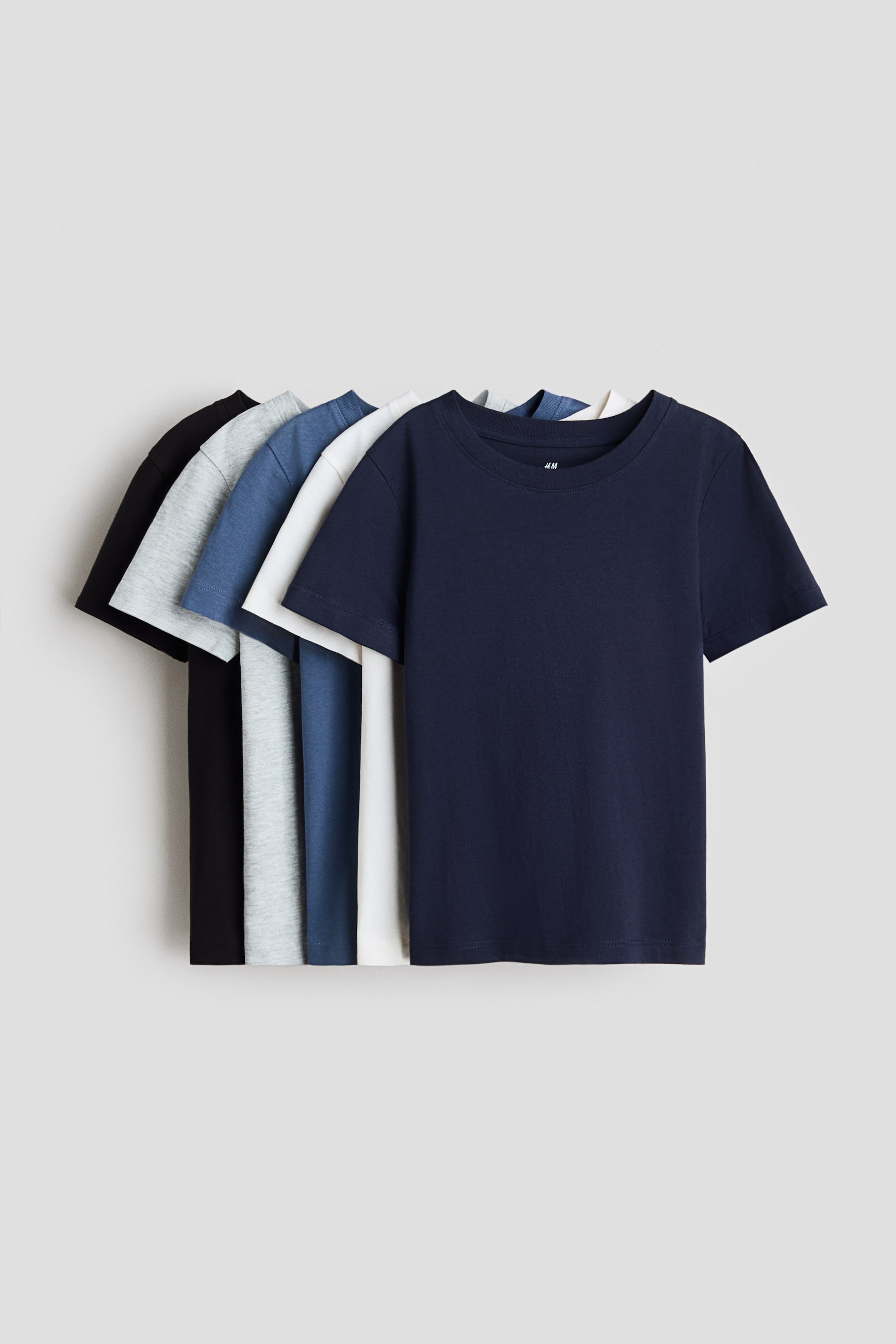View larger image: Five t-shirts made of soft cotton jersey are showcased from the front, stacked and fanned out. They feature round necklines and straight-cut hems in navy blue, white, blue, light gray, and black.