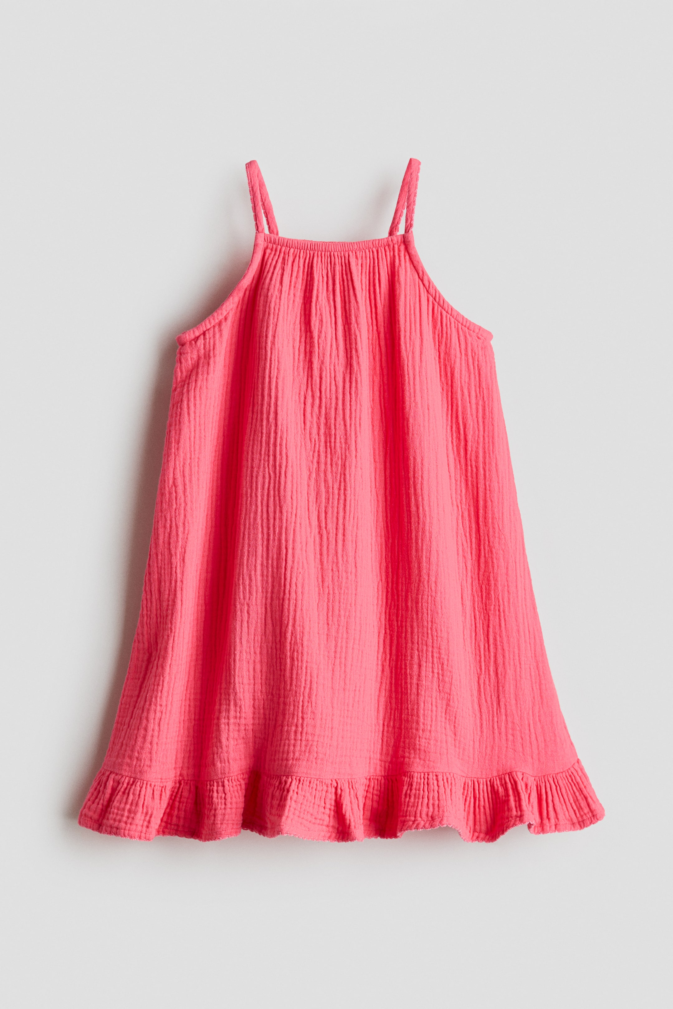 Größeres Bild ansehen: Ein leuchtend pinkfarbenes A-Linien-Kleid präsentiert seine Vorderseite, gefertigt aus einem gewebten Stoff. Es verfügt über einen quadratischen, elastischen Ausschnitt, einen schmalen Schnitt am Oberteil, schmale Träger und einen Volant am Saum.