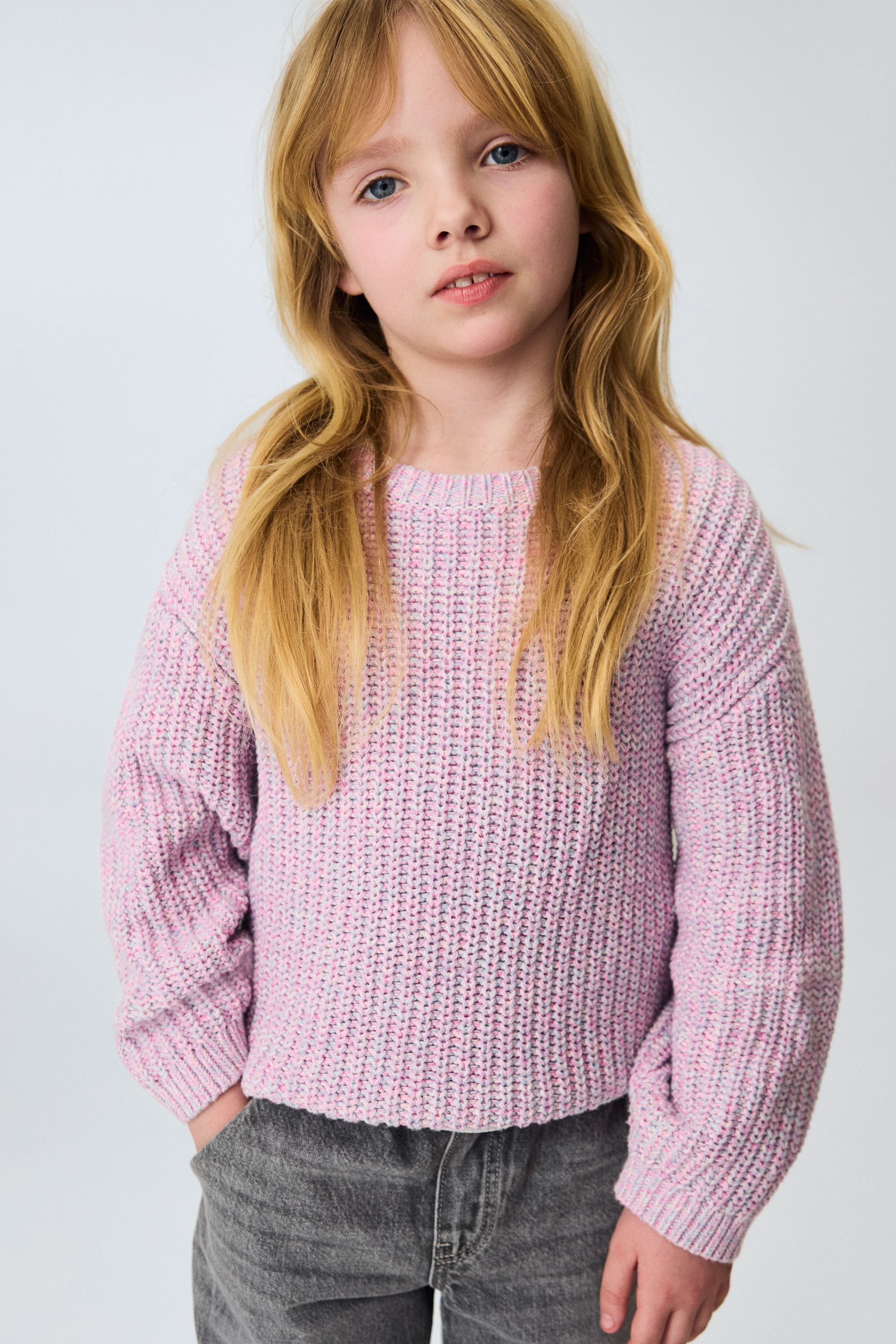 View larger image: The pink marled textured knit jumper features a round neck, long sleeves with ribbed cuffs, and a ribbed hem. It is worn with a relaxed fit, with its ribbed hem sitting at the hips.