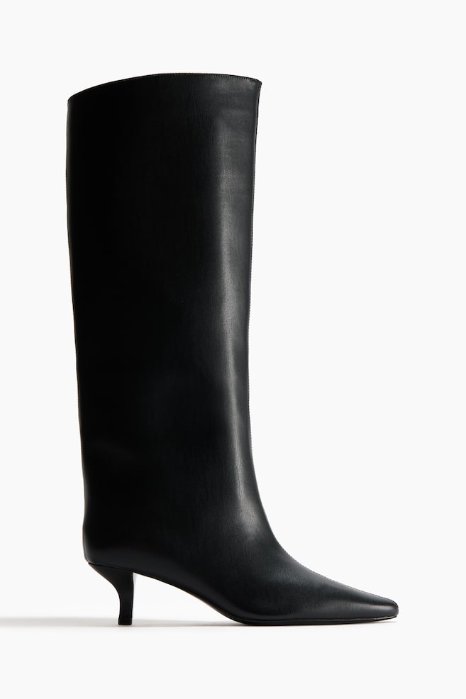 A black knee-high boot is featuring a pointed toe and a partially covered kitten heel. The boot's shaft is presenting a smooth texture and curving gently at its top edge. - 1