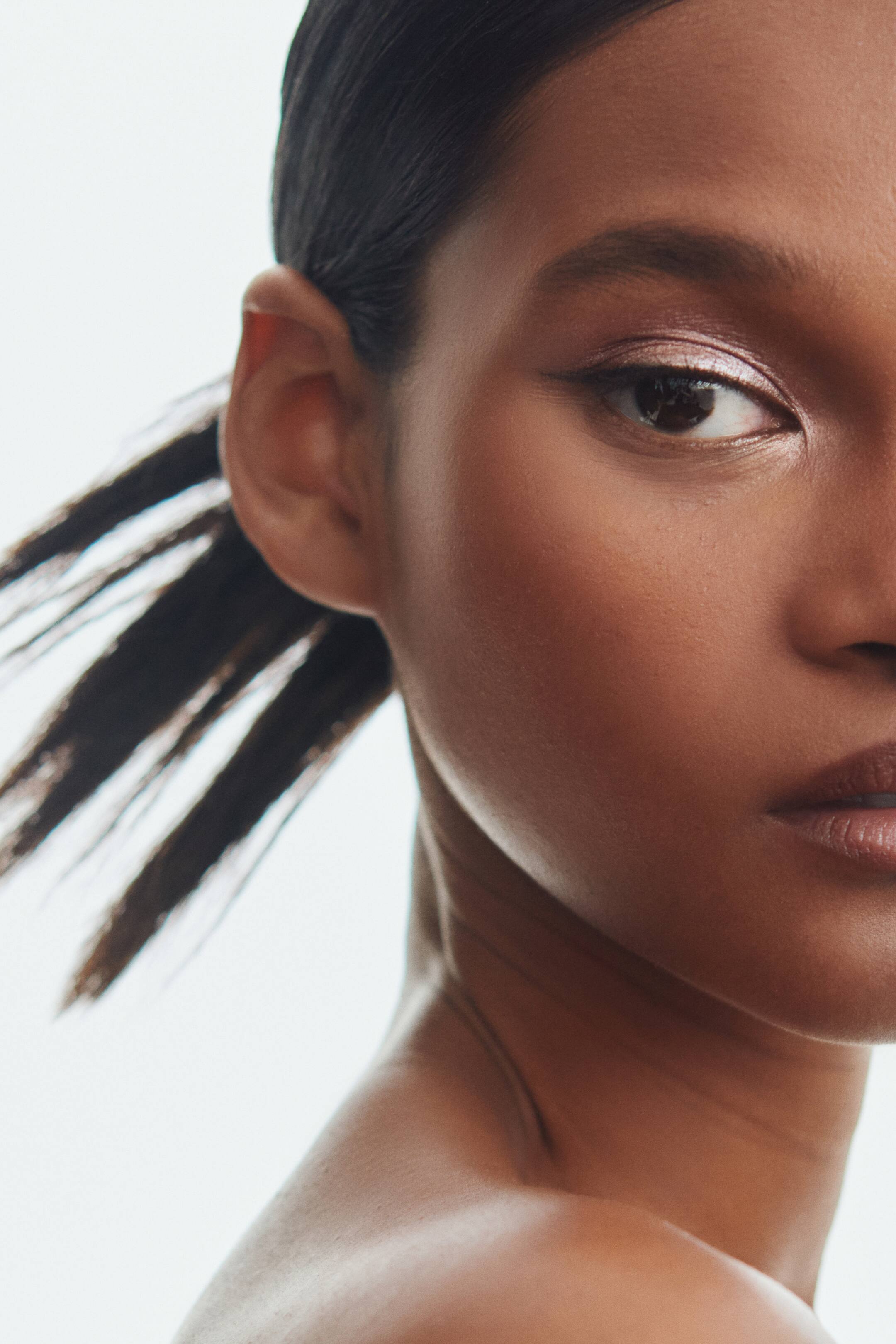 Преглед на по-голямо изображение: Течни сенки за очи с блестящо, медно-розово покритие са нанесени върху клепача на модела.