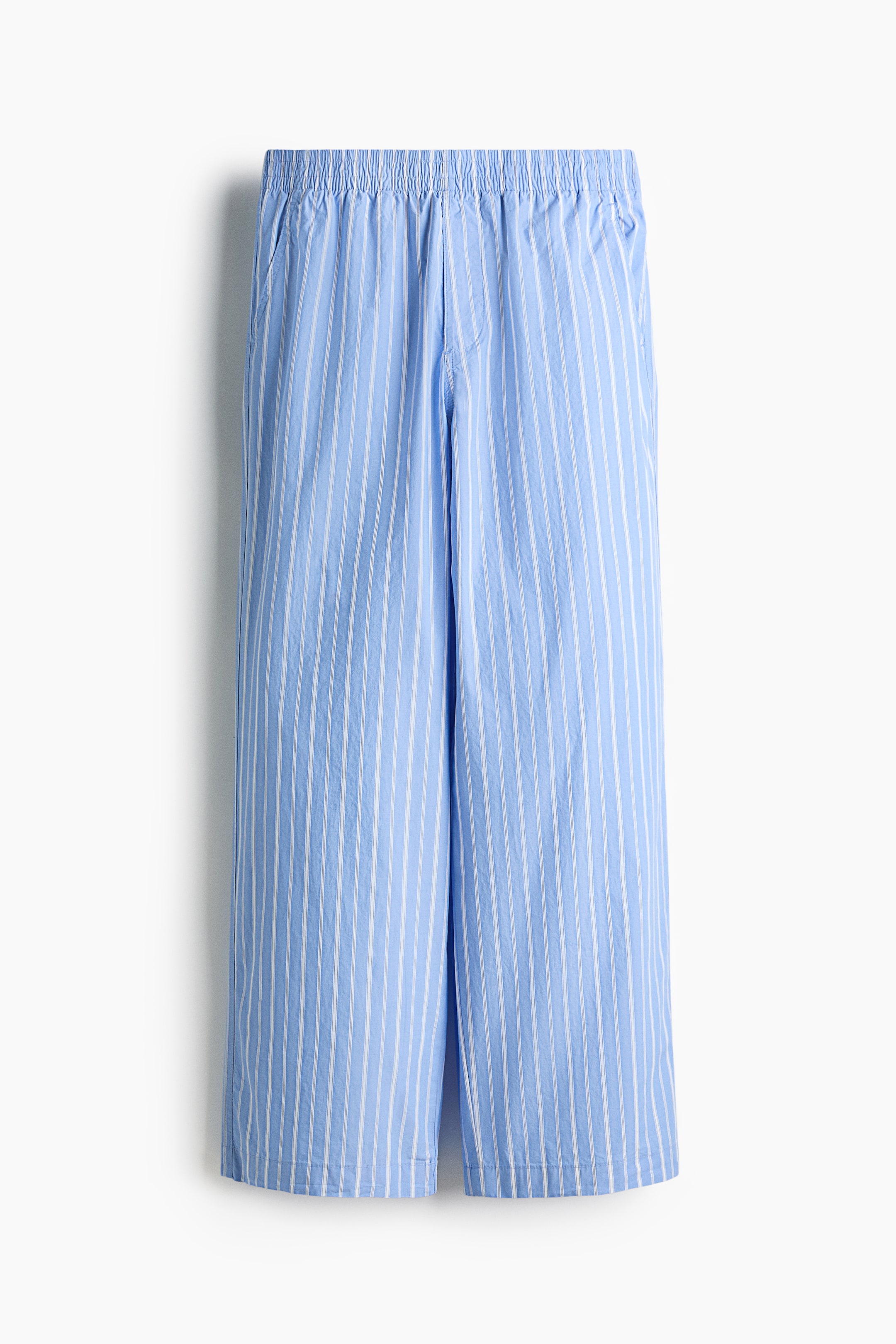 View larger image: A pair of light-blue pants with thin vertical white stripes is shown from the front, featuring an elasticized, ruched waistband and two side pockets. The pants are styled with a relaxed, straight leg and a simple hem.