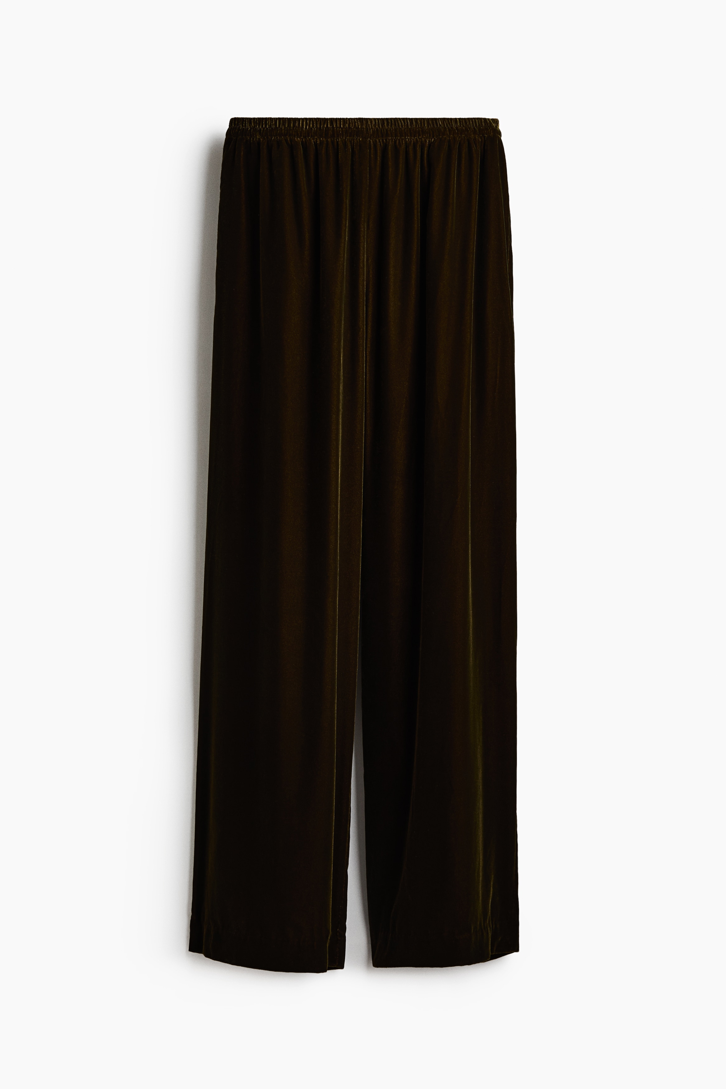 Manekenka nosi tamnosmeÄe somotske pantalone Å¡irokog kroja sa elastiÄnim pojasom. Pantalone su stilizovane uz belu Å¡iroku bluzu sa visokim okovratnikom.