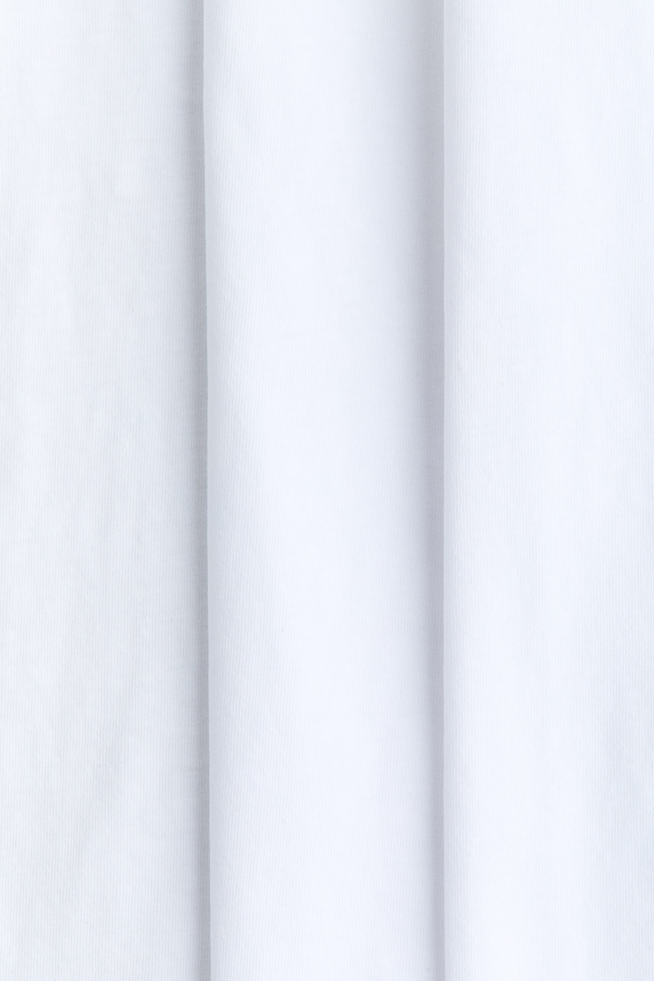Se større billede: Løse T-shirts viser en nærbillede af deres bløde hvide bomuldsjersey, som er elegant draperet i lodrette folder.