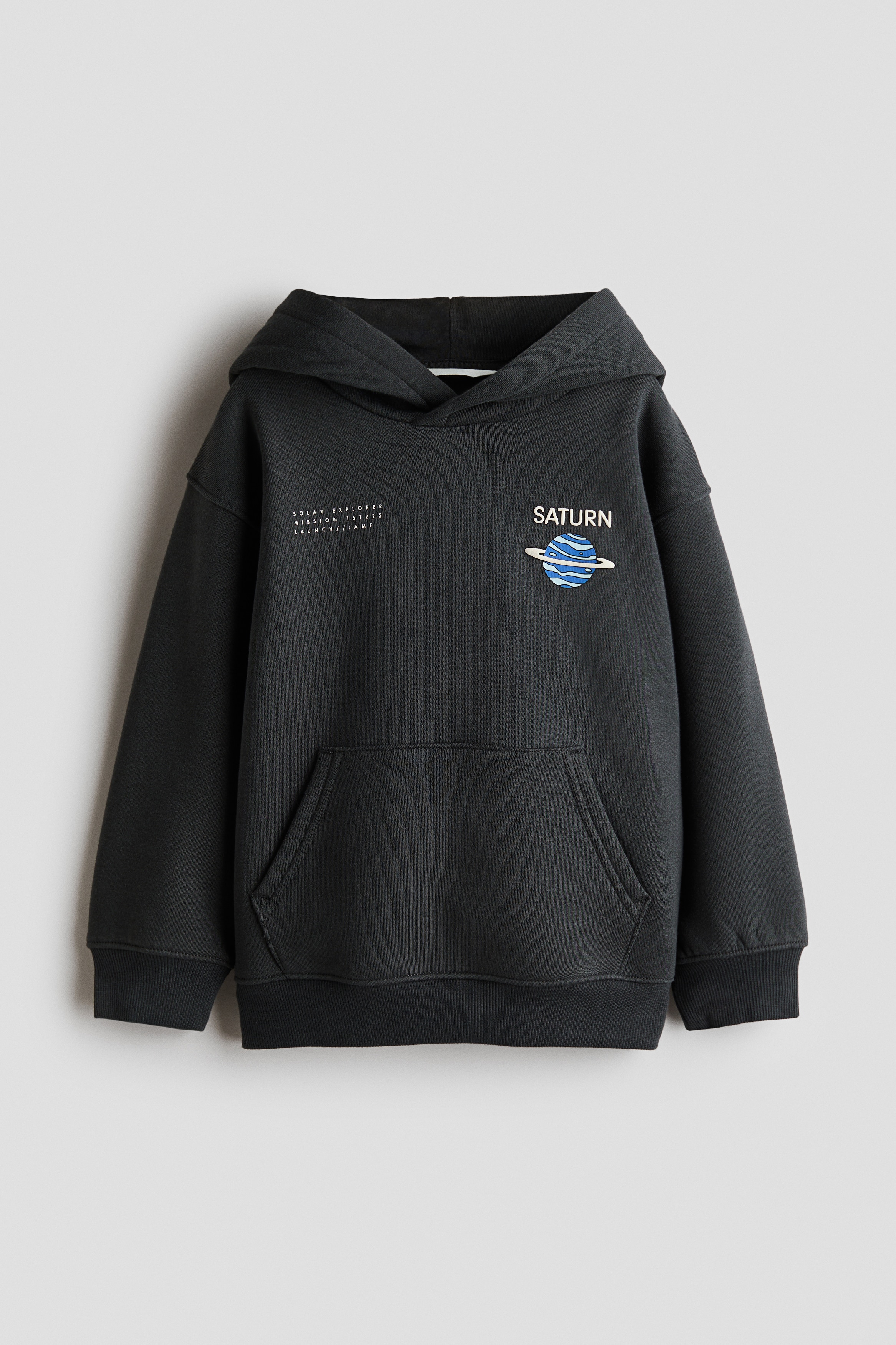 Een donkergrijze hoodie met losse pasvorm wordt van achteren getoond, met een grote grafische print van het zonnestelsel met kleurrijke planeten en witte tekst met de woorden "THE SOLAR SYSTEM". De hoodie is ontworpen met verlaagde schouders, een nonchalante capuchon en brede geribde boorden aan de mouwen en onderzoom.