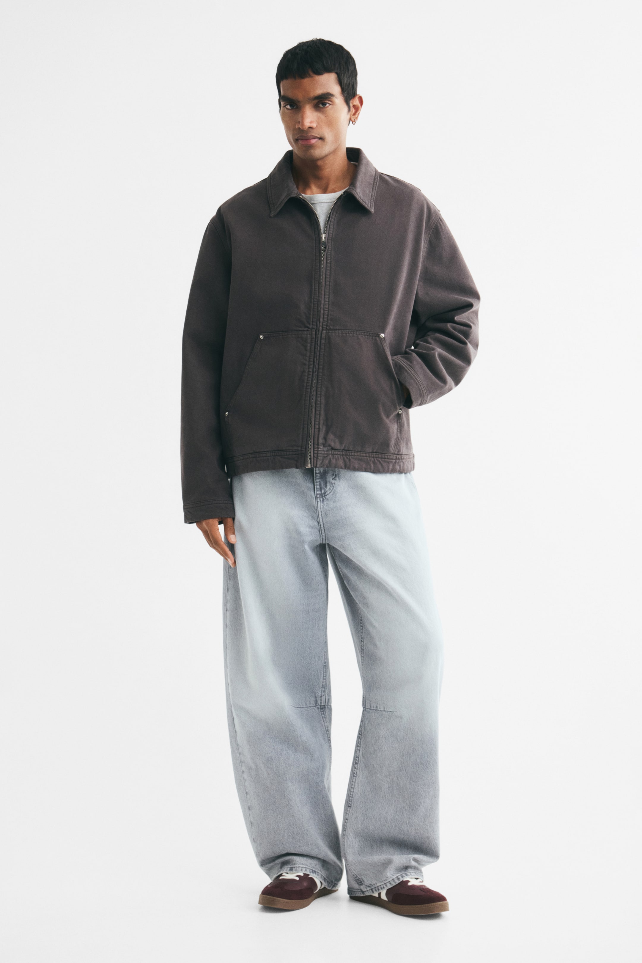 View larger image: The model is wearing 5-pocket jeans in light blue rigid cotton denim. They feature a regular waist, a zip fly, and barrel legs with a baggy fit from the seat to the hem.