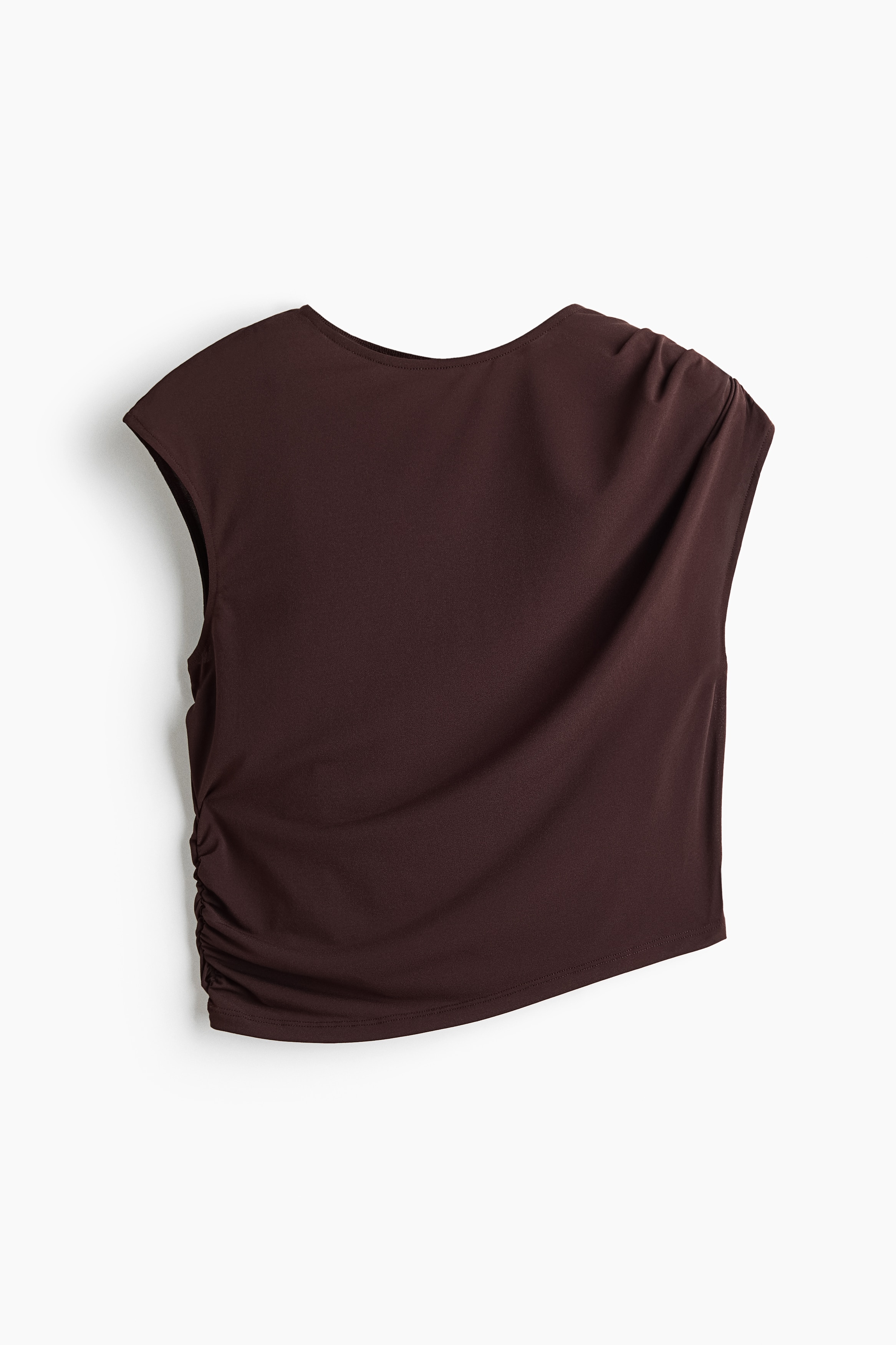 A dark brown stretch jersey top featuring a round neckline, cap sleeves, and a draped bodice is worn by the model. The top features pleats on one shoulder and a gathered side seam, creating an asymmetrical cropped hem styled with matching draped bottoms.