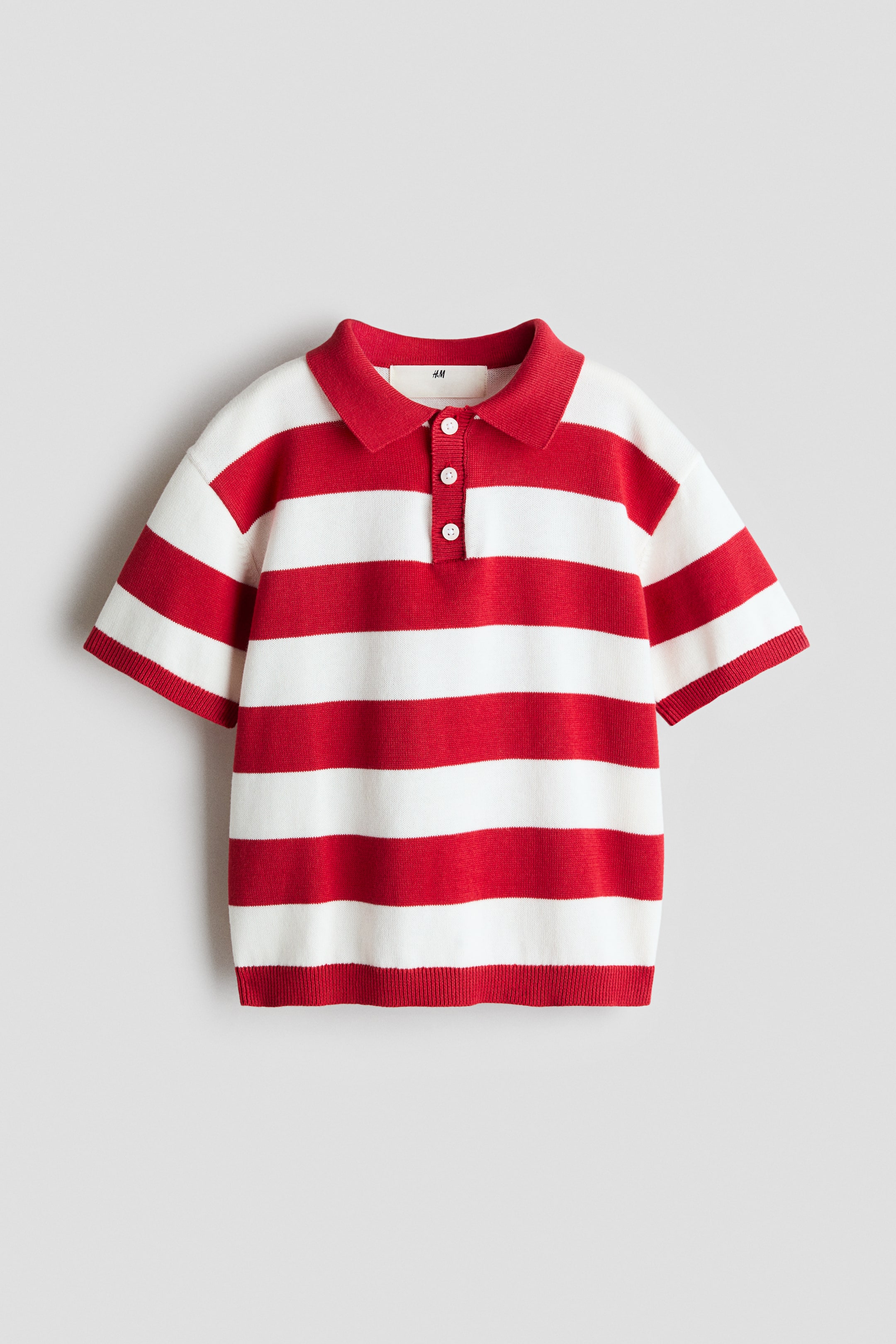 View larger image: A polo shirt crafted in a soft cotton knit showcases red and white horizontal stripes. It features a plain-knit collar, a three-button placket, dropped shoulders, and short sleeves with ribbed cuffs and a ribbed hem, all viewed from the front.