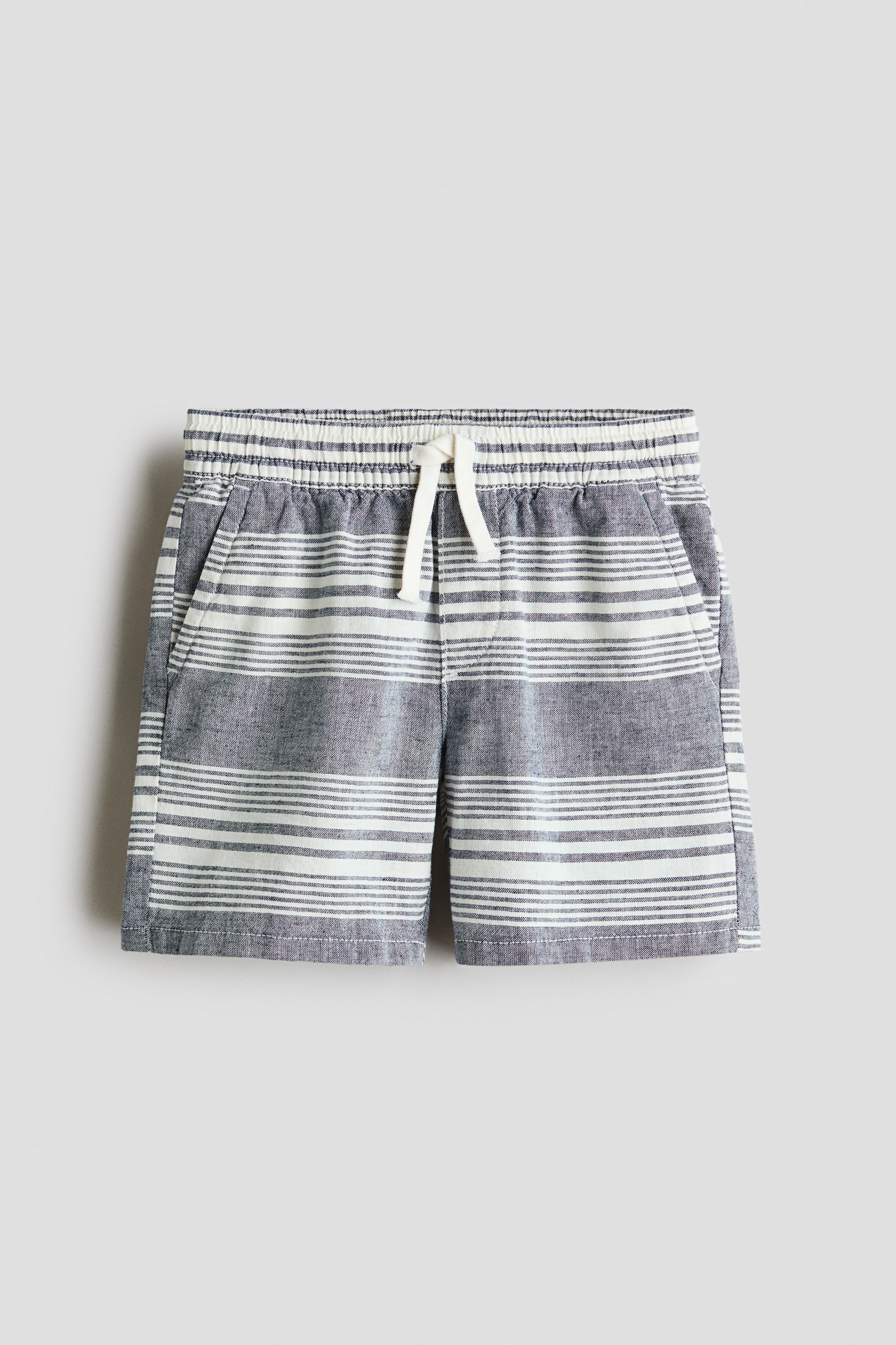 View larger image: The front of the shorts is featuring grey and white horizontal stripes, an elasticated, gathered waistband with a white drawstring tie, and two visible side pockets.
