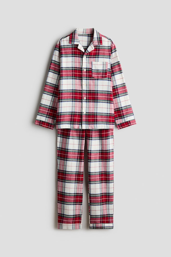 Ein zweiteiliger Pyjama-Set zeigt von vorne ein passendes langÃ¤rmliges Oberteil und eine gerade geschnittene Hose in einem rot-weiÃ-grÃ¼nen Karo-Muster. Das Oberteil verfÃ¼gt Ã¼ber eine durchgehende Knopfleiste mit Reverskragen und eine aufgesetzte Brusttasche auf der linken Seite. - 1