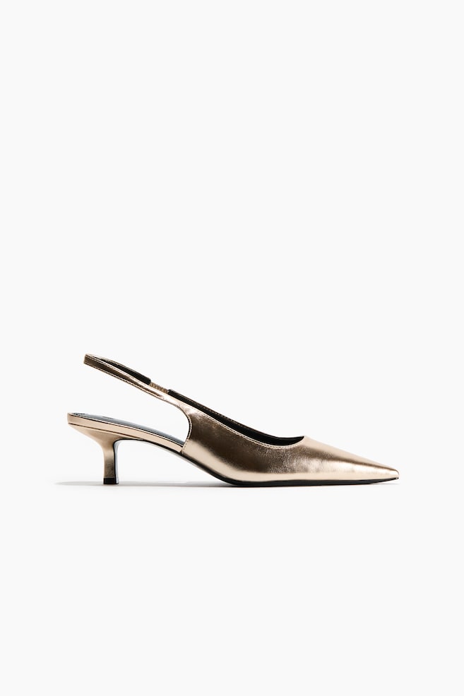 A metallic gold slingback shoe is shown in a side profile facing right, featuring a pointed toe, a narrow ankle strap with a black elasticated insert, and a low, partially covered kitten heel. - 1