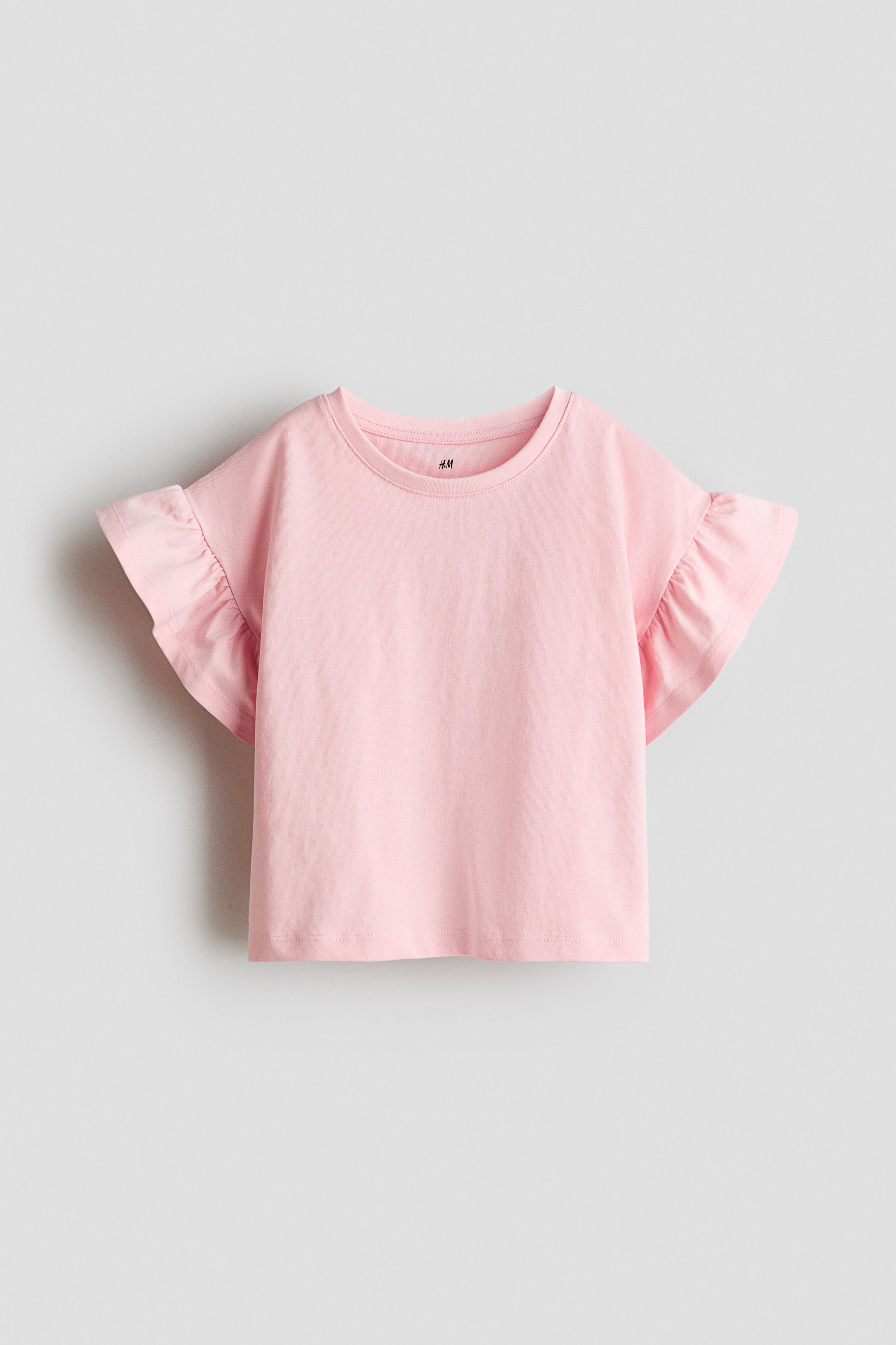 拡大画像を表示: ピンクのボクシートップが正面から紹介されており、丸いリブトリムのネックライン、低く落ちたショルダー、そしてフラッタースリーブが特徴です。