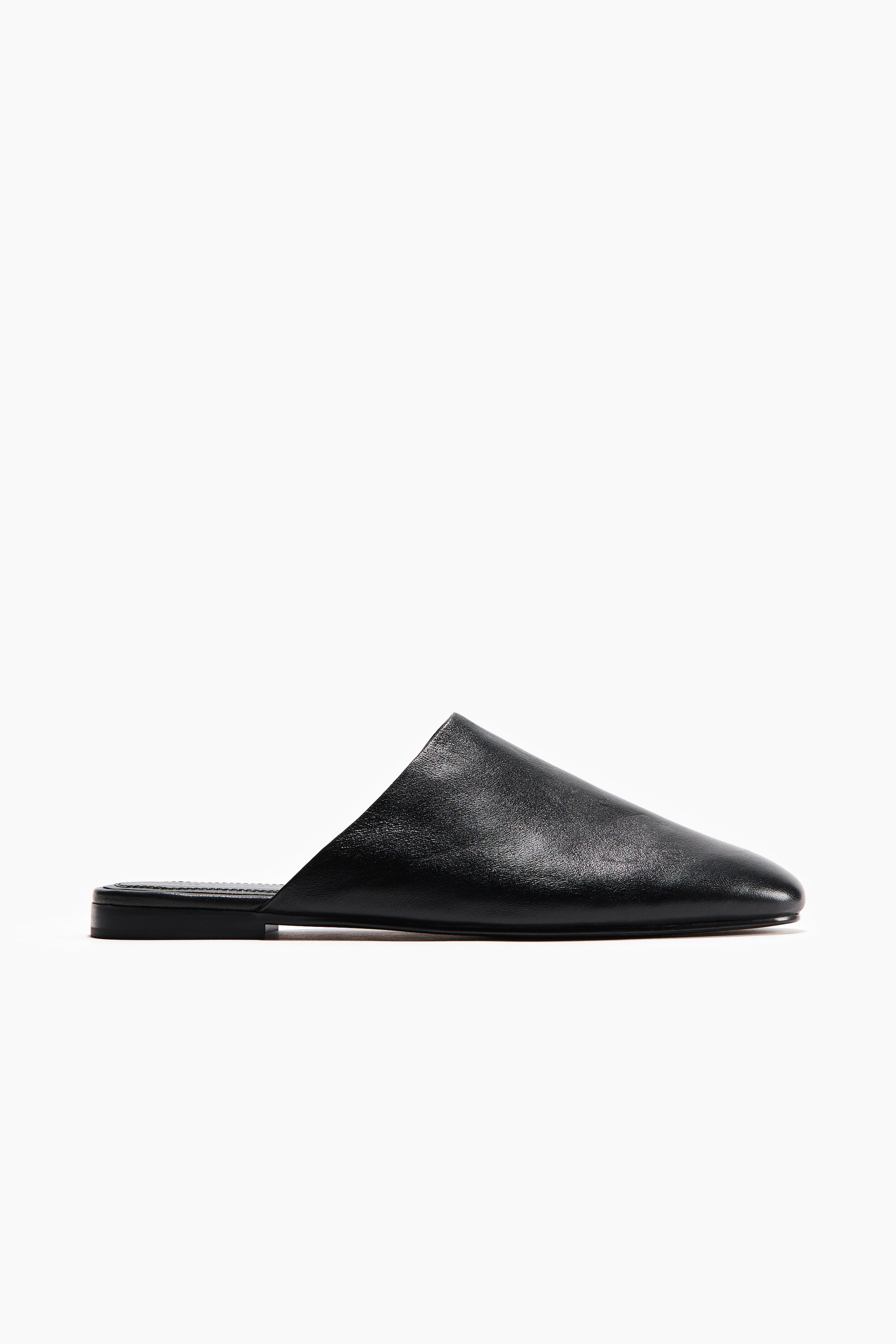 Ver imagen más grande: Una mula de cuero negro con parte superior lisa, punta afilada y suela plana con costuras visibles en el borde.