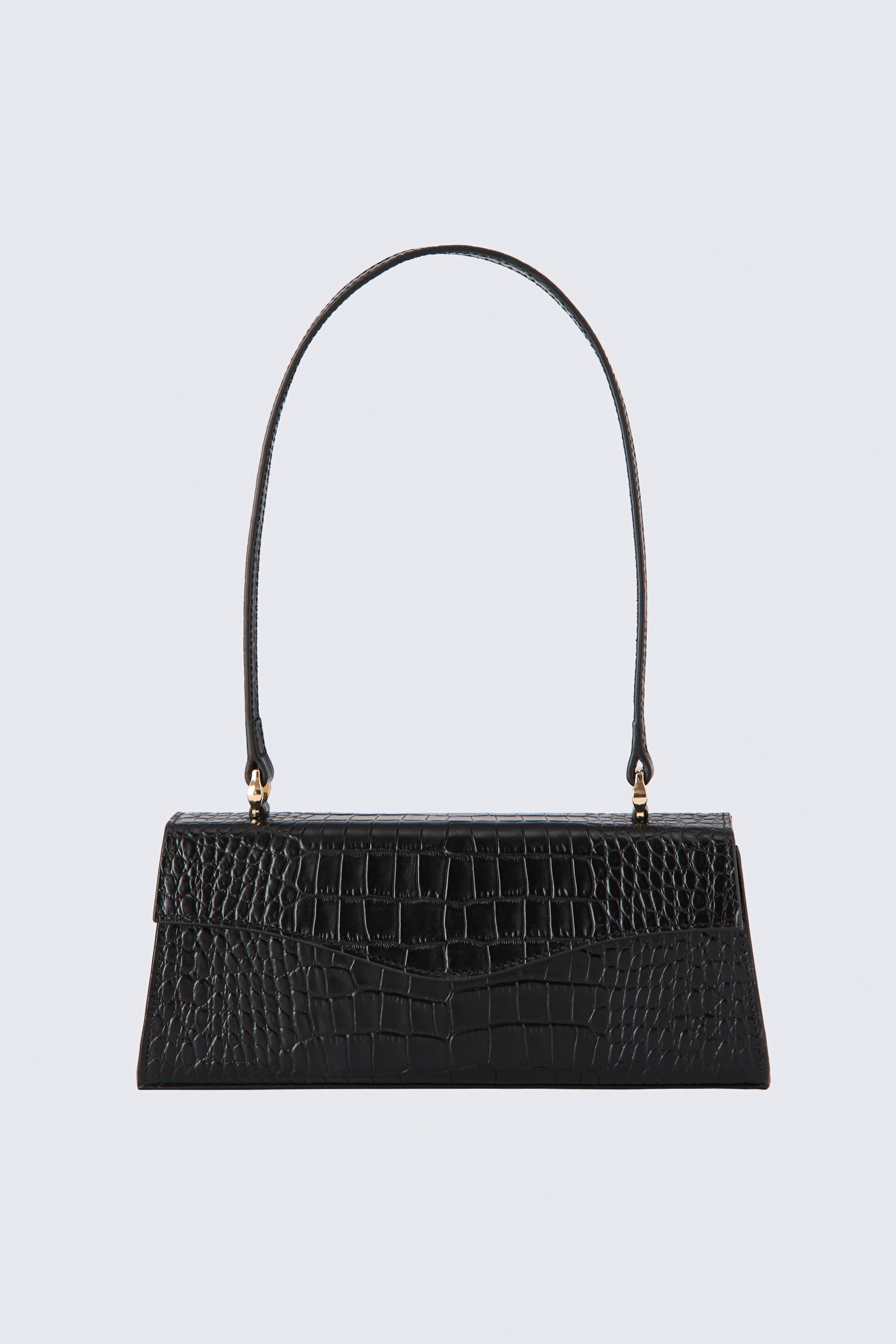 Agrandir l'image: Un sac bandoulière en cuir noir est présenté de face, mettant en valeur une forme structurée trapézoïdale avec une texture embossée façon crocodile. Le sac présente un rabat frontal incurvé et une longue bandoulière arquée et fine, fixée par des finitions métalliques dorées.