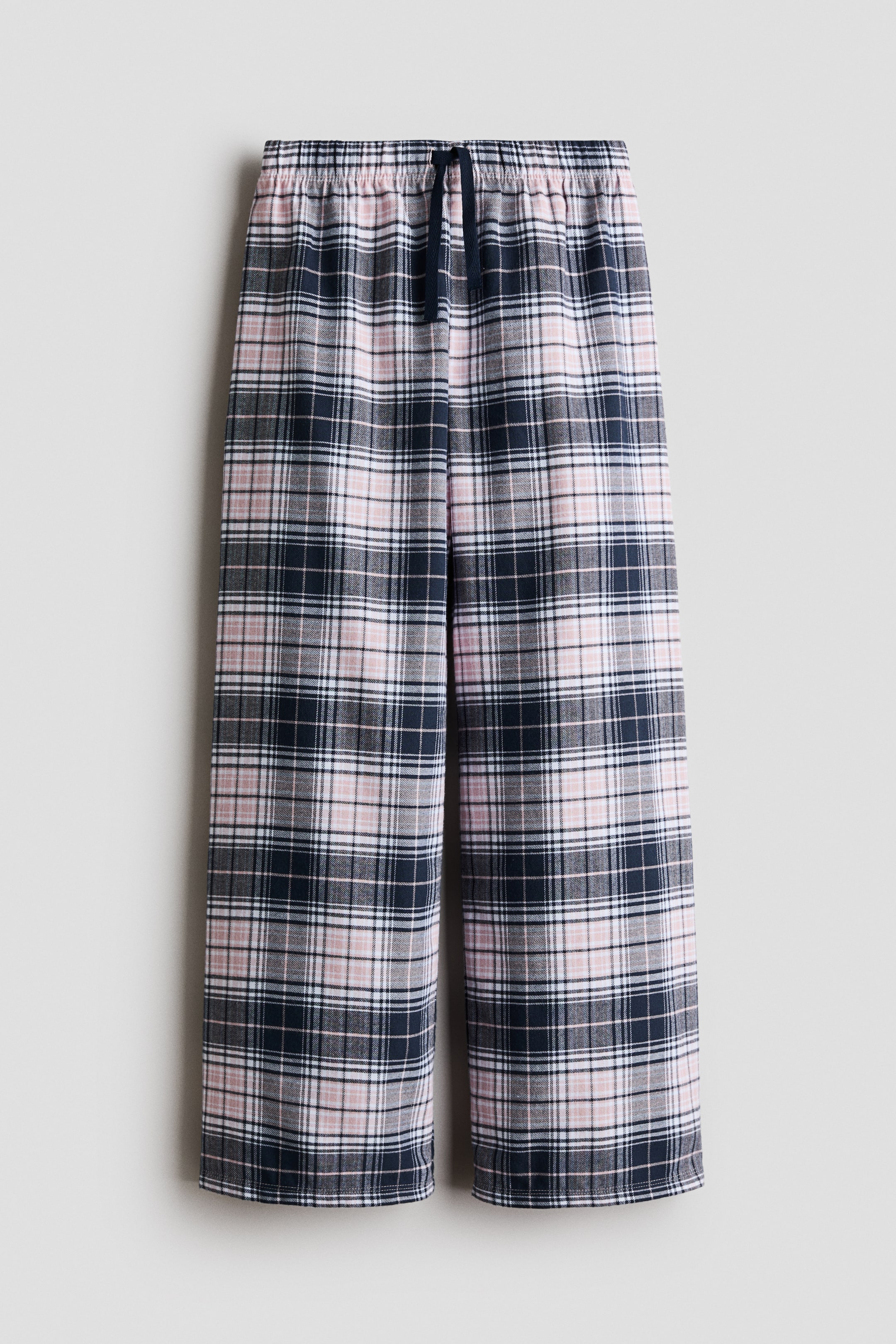 View larger image: Pajama pants showcase a plaid pattern in navy blue, pink, white, and thin black lines. They feature an elasticized waistband with a navy blue drawstring and straight-leg openings.