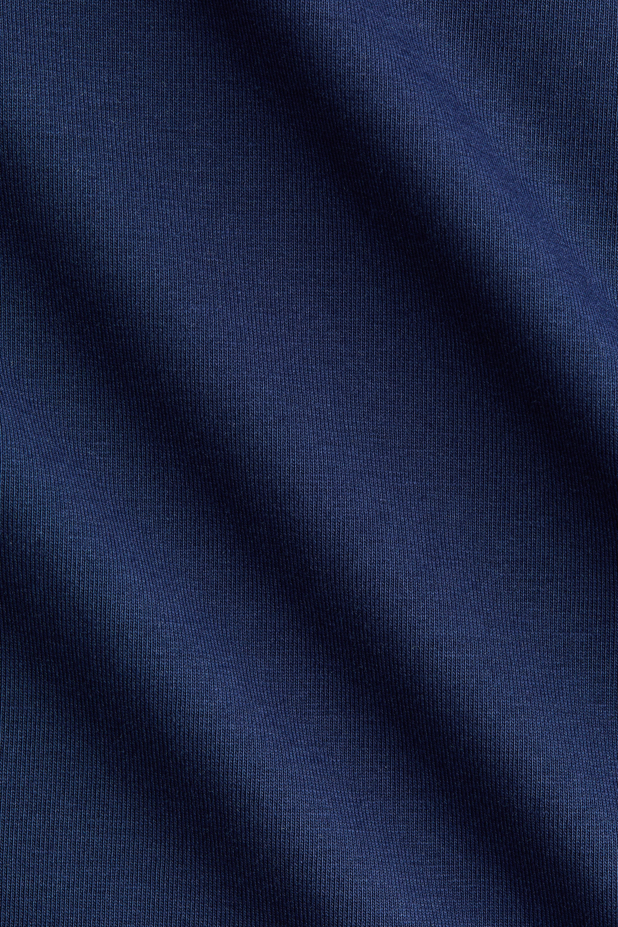 Voir une image plus grande: Le jersey de coton extensible du t-shirt ajusté affiche un bleu foncé et une fine texture côtelée verticale.