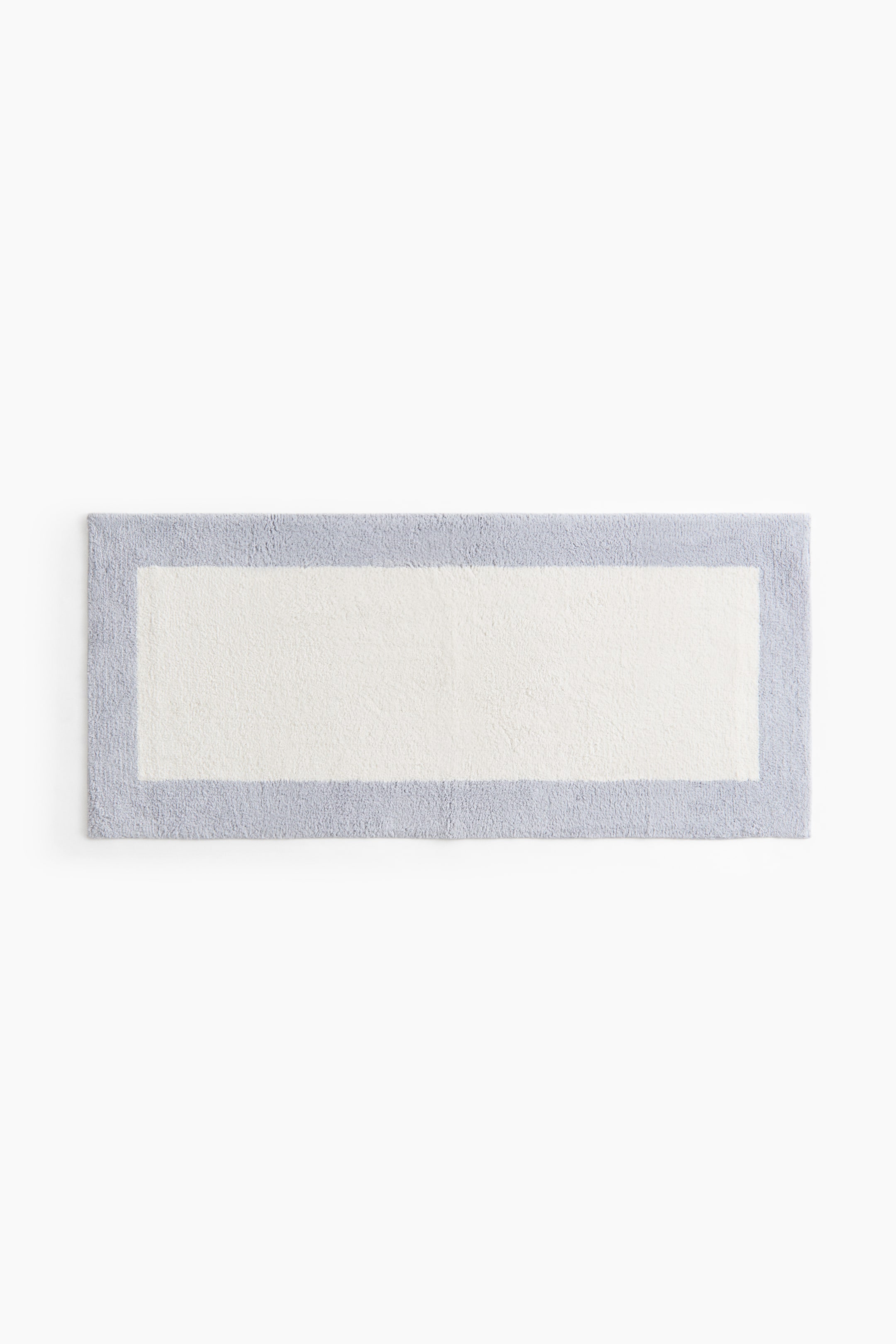 View larger image: "A rectangular tufted cotton bath mat is showcased from the front, featuring an off-white central panel framed by a light blue border."