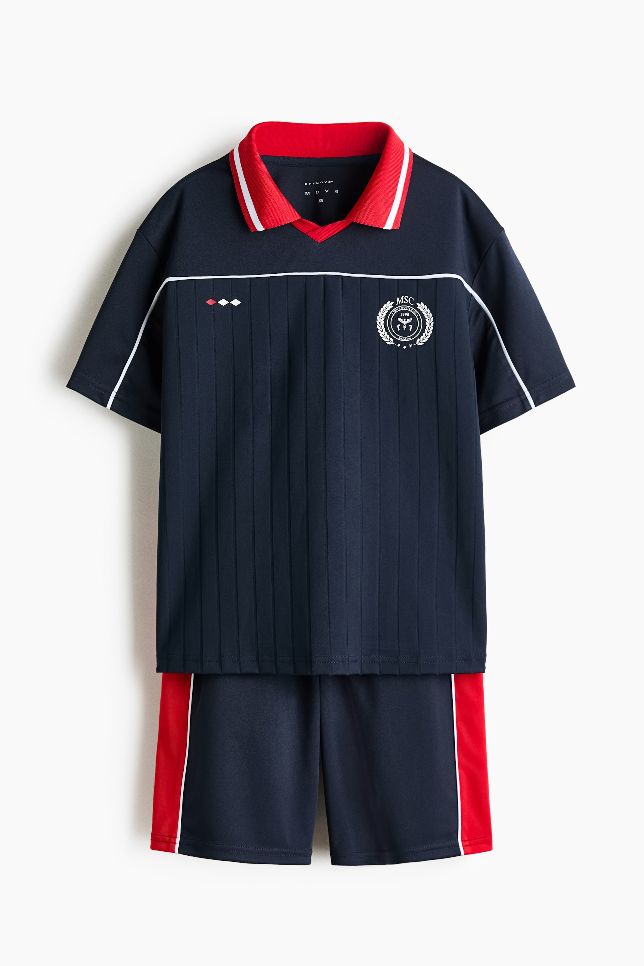 Zobacz większy obraz: Granatowy zestaw sportowy prezentuje się z przodu, zawierając koszulkę polo z krótkim rękawem, z kołnierzykiem w czerwono-białe paski, pionowymi prążkami, białymi lamówkami na ramionach, poziomym białym paskiem na klatce piersiowej, białym okrągłym emblematem na prawej piersi oraz trzema małymi diamentowymi kształtami na lewej piersi. Pasujące granatowe szorty mają czerwony pionowy pasek z cienkim białym paskiem po każdej stronie.