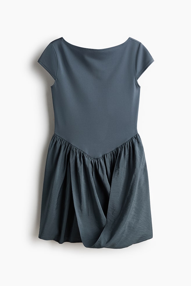 Presenting a dark teal dress in its front view, this piece features a fitted bodice with short cap sleeves and a boat neckline. The bodice seamlessly transitions into a gathered skirt at a V-shaped waistline. The skirt is highlighted by a draped, asymmetrical front detail, accentuated with a subtle crinkle texture. - 1